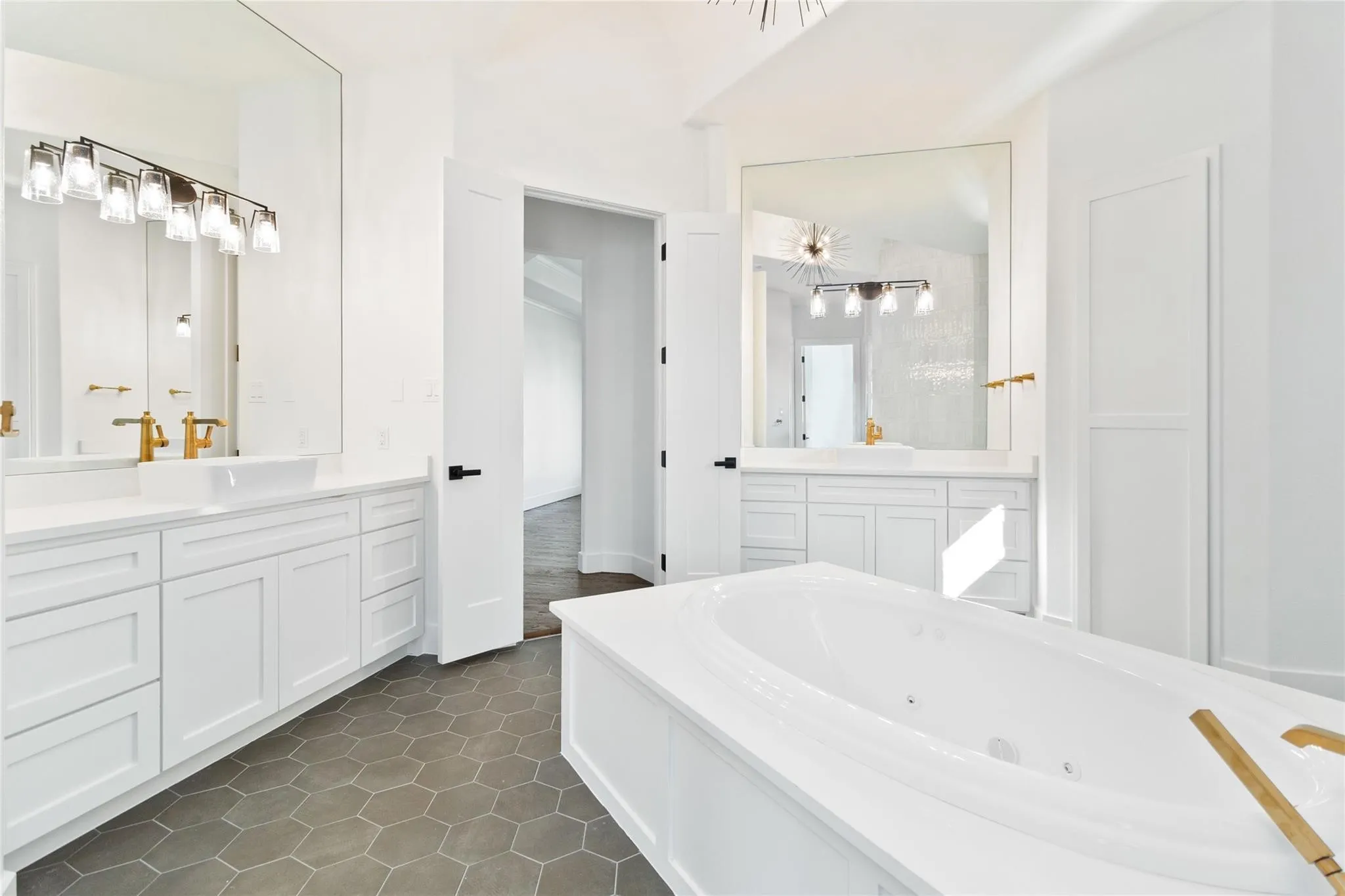 Dual vanities with white cabinetry, hexagonal floor tiling, and a built-in soaking tub