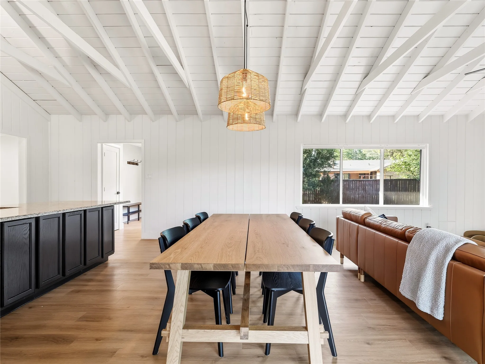 Vaulted ceiling with exposed beams, wood-finish flooring, white shiplap walls, recessed lighting, and a large window