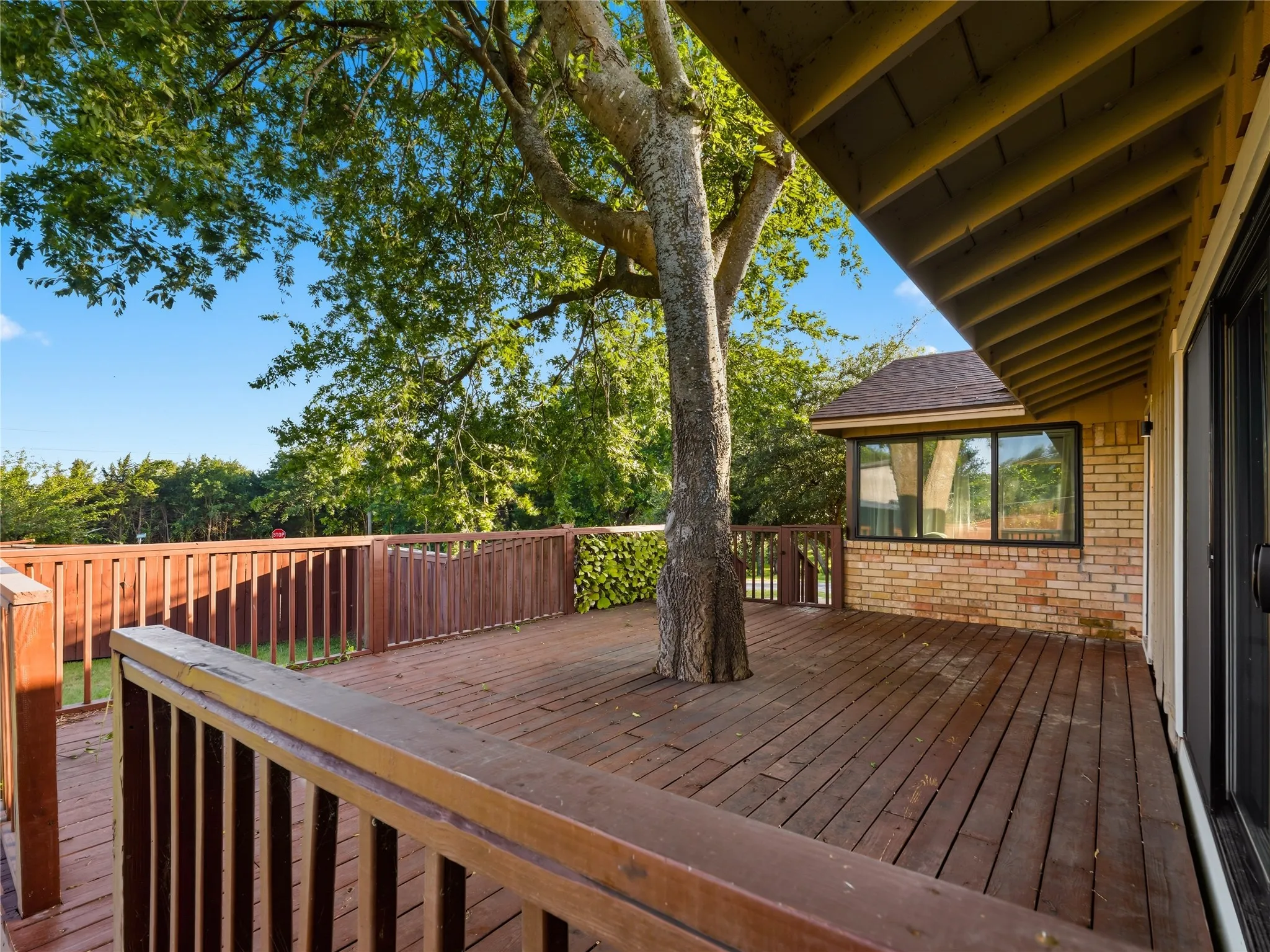 Expansive wood deck with full railing and integrated mature tree