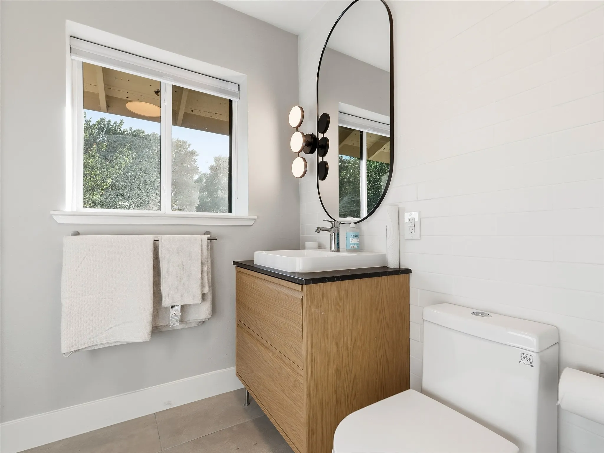 Wood-finish vanity with a rectangular vessel sink and dark countertop