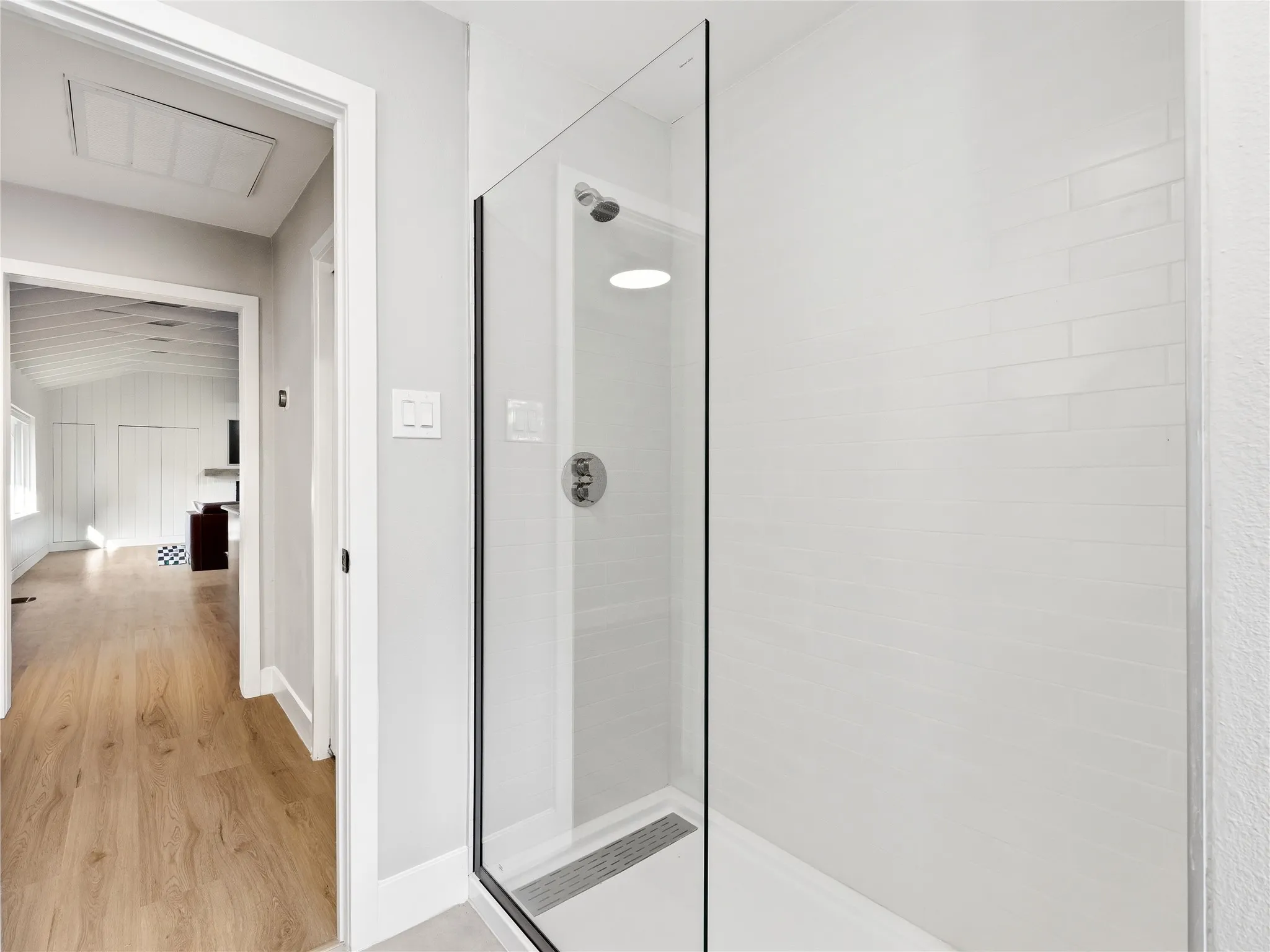 Glass-enclosed shower with subway tile surround, recessed shower light, and matte silver fixtures