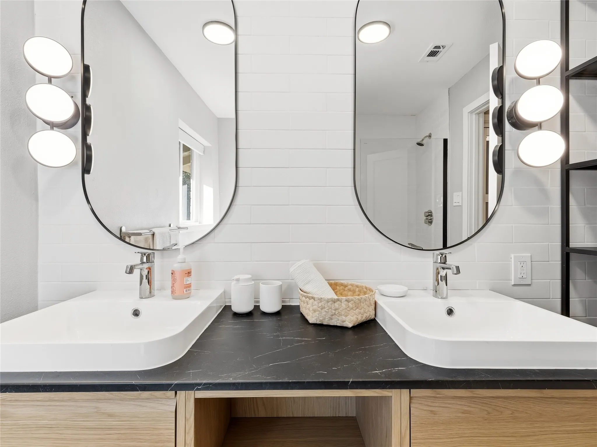 Dual vanity with integrated white rectangular sinks, a dark countertop, and light wood-finish cabinetry