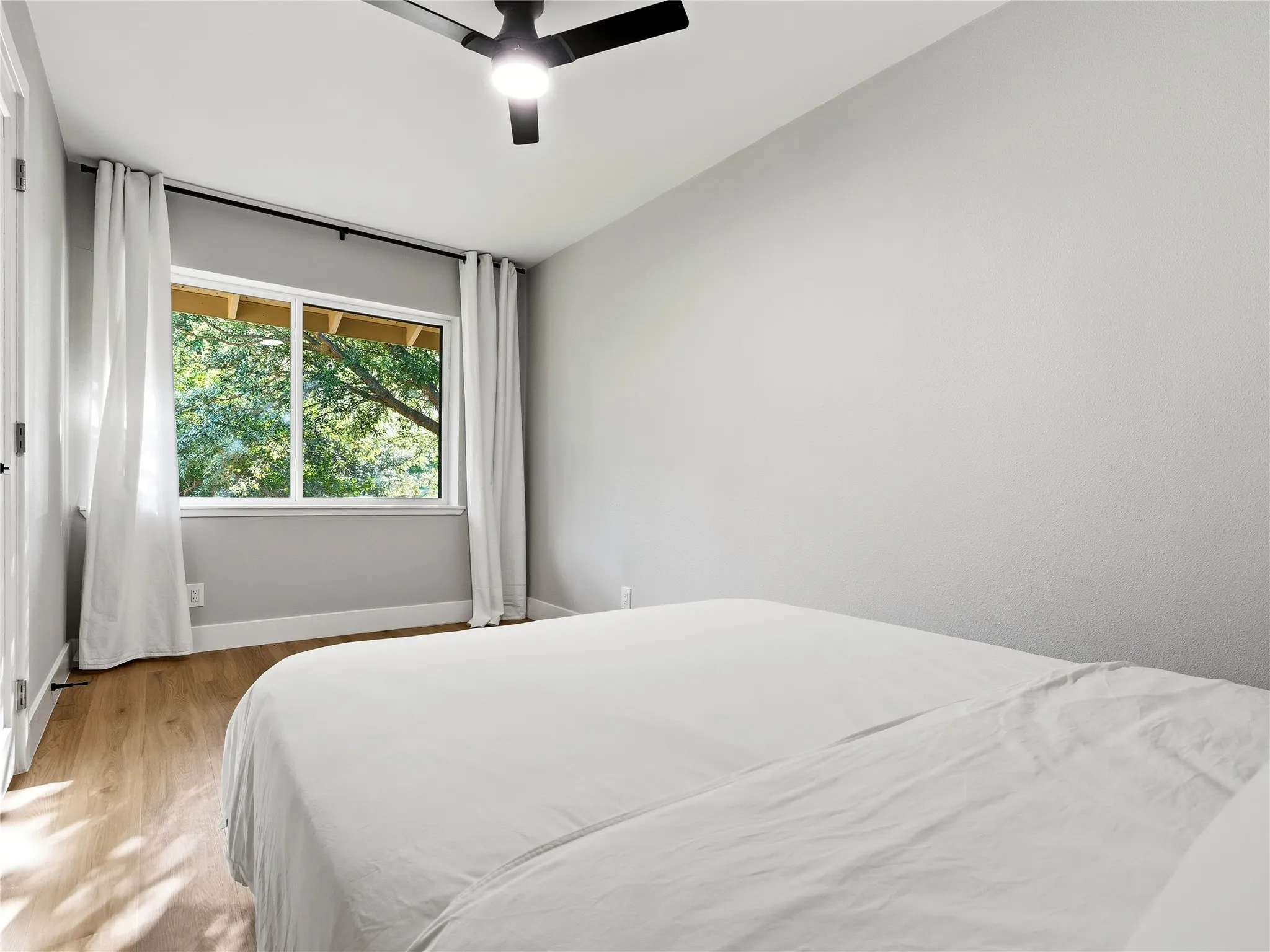 Recessed window with white trim, wood-finish flooring, and a ceiling fan with integrated lighting