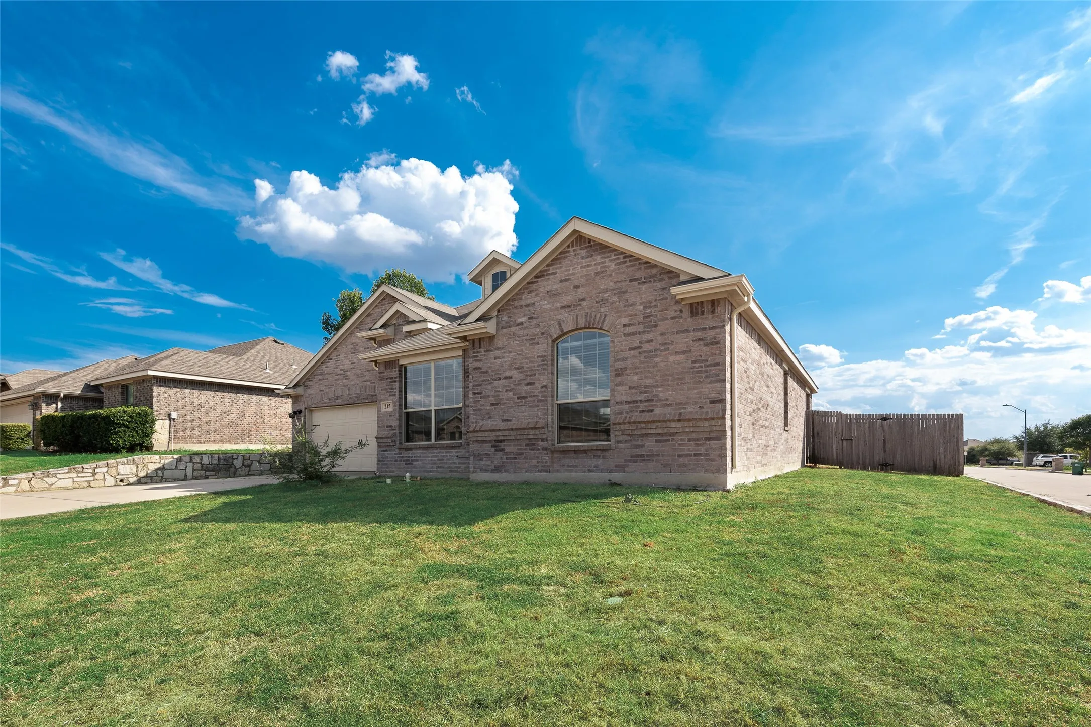 Brick exterior with an attached garage, arched window, and gabled roofline