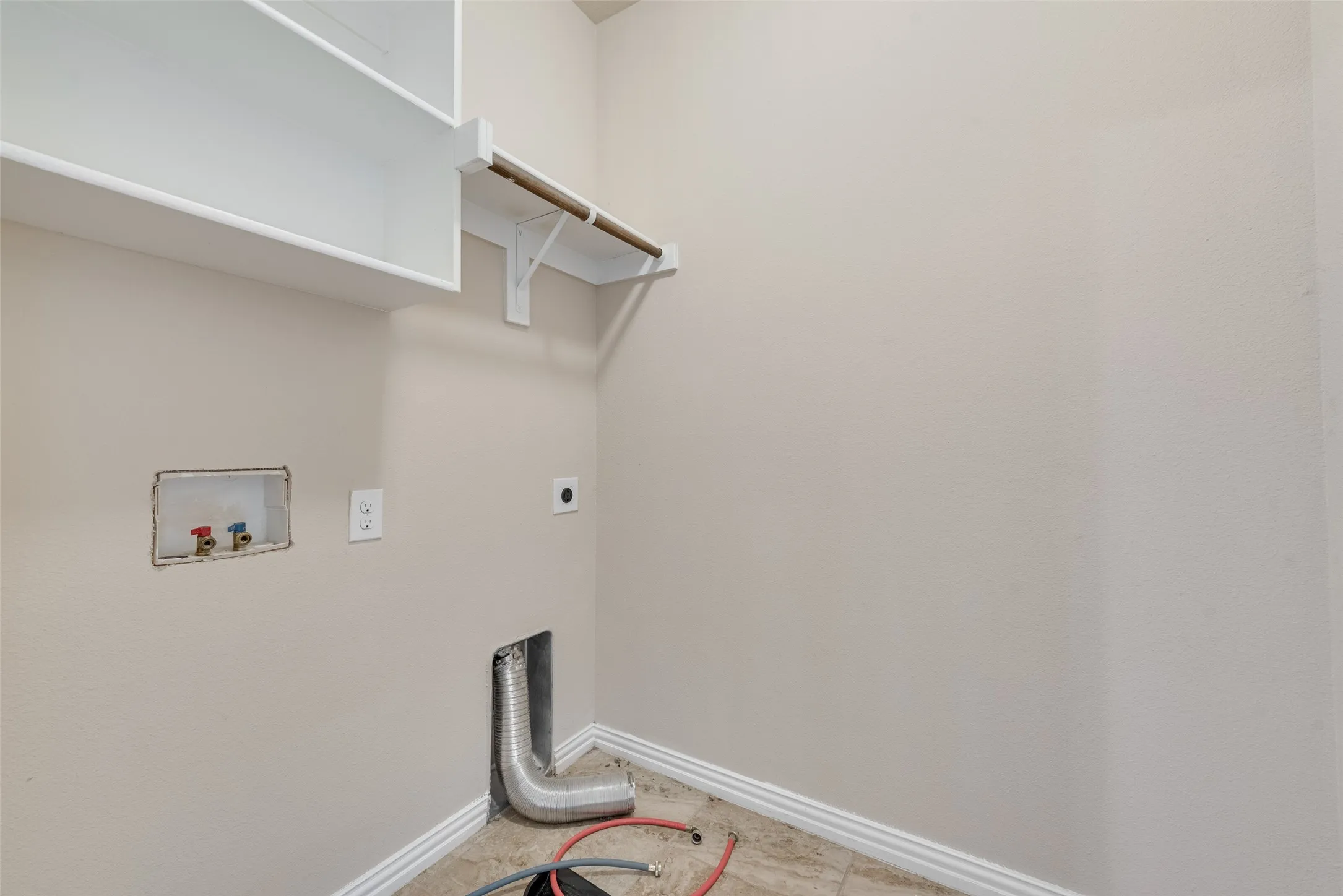 Utility area with upper shelving, clothes hanging rod, and appliance hookups