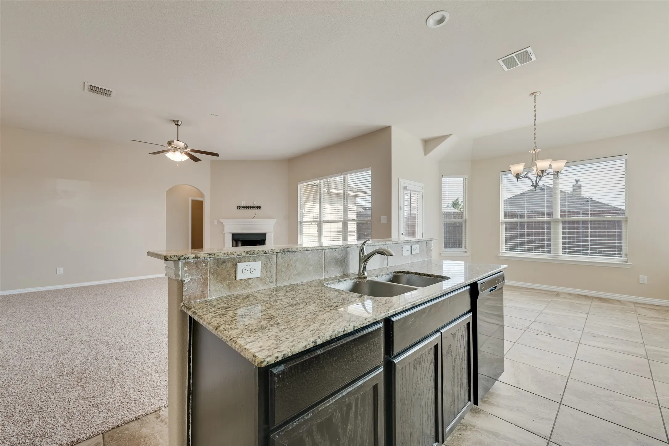 Kitchen island with granite countertops, double basin sink, and integrated dishwasher