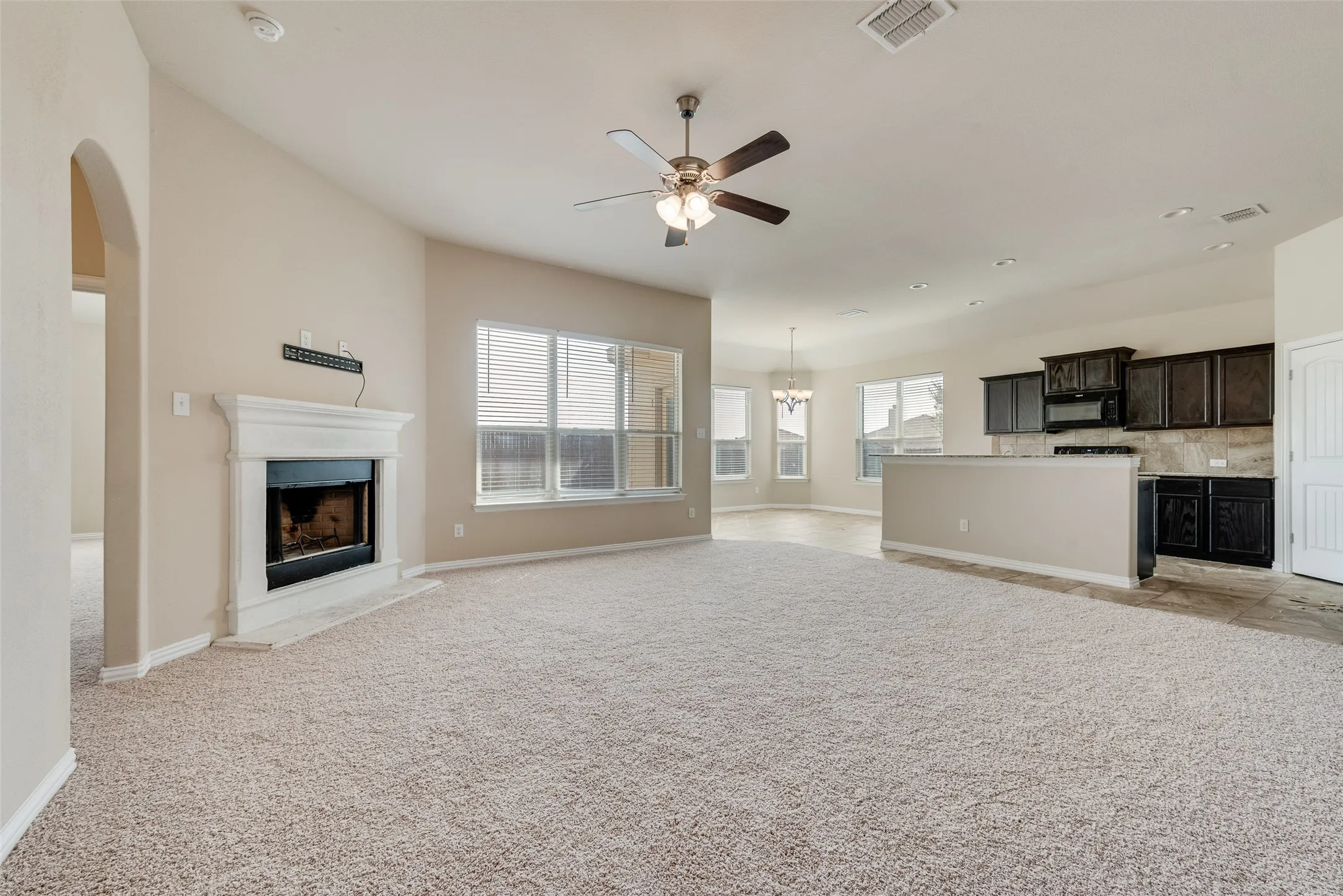 Expansive living area with vaulted ceilings, a fireplace, and large windows