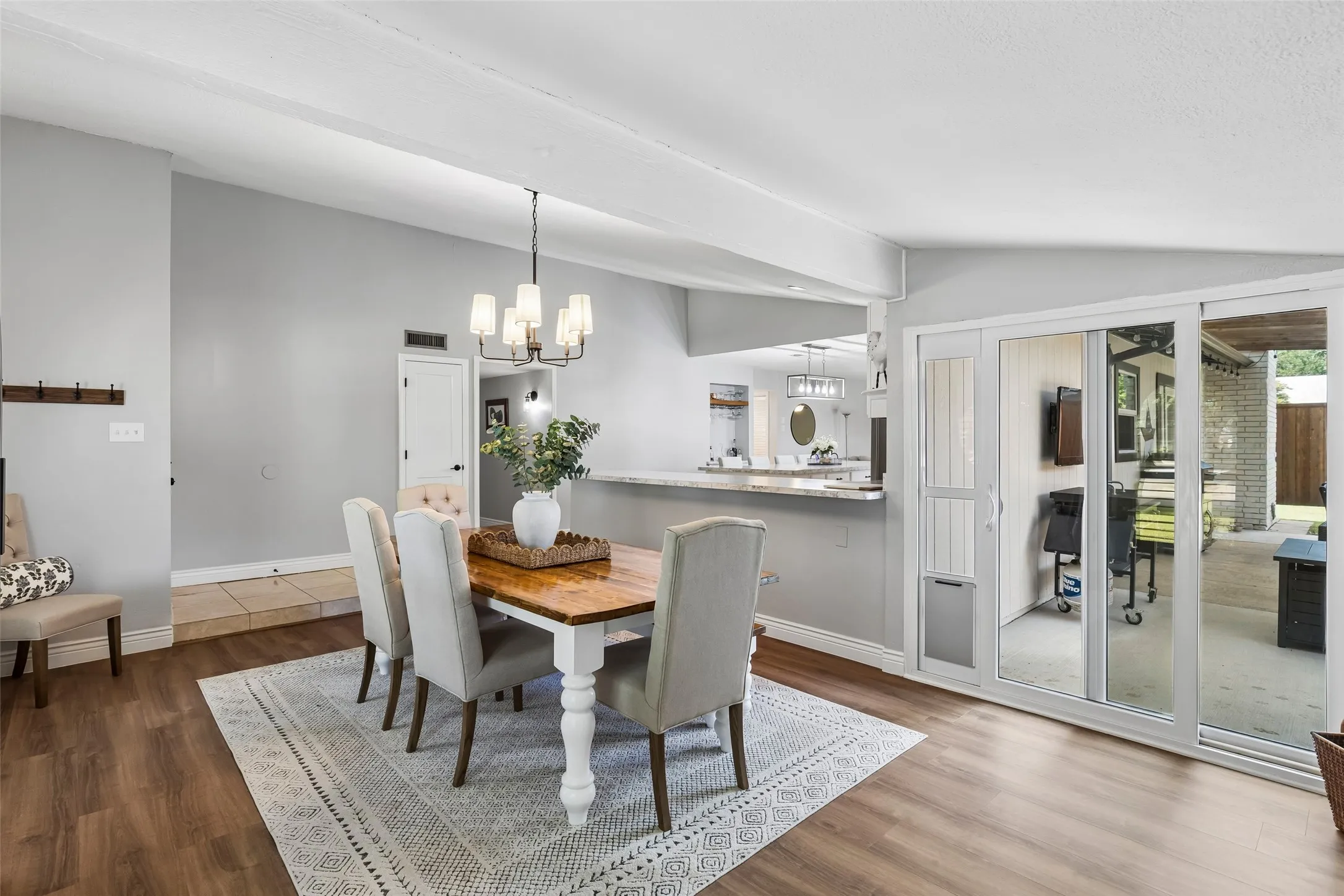Glass doors on both sides pull the dining space toward the patio and yard, keeping the whole downstairs connected.