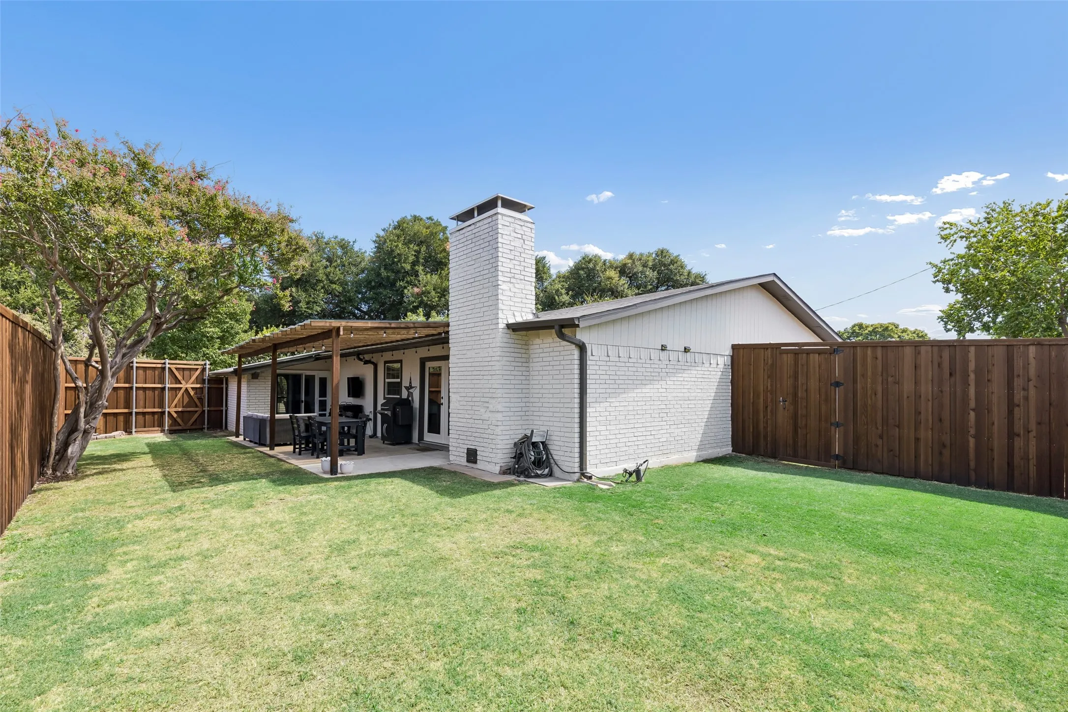 The painted brick exterior extends around back, with a gated side yard for extra storage or access.