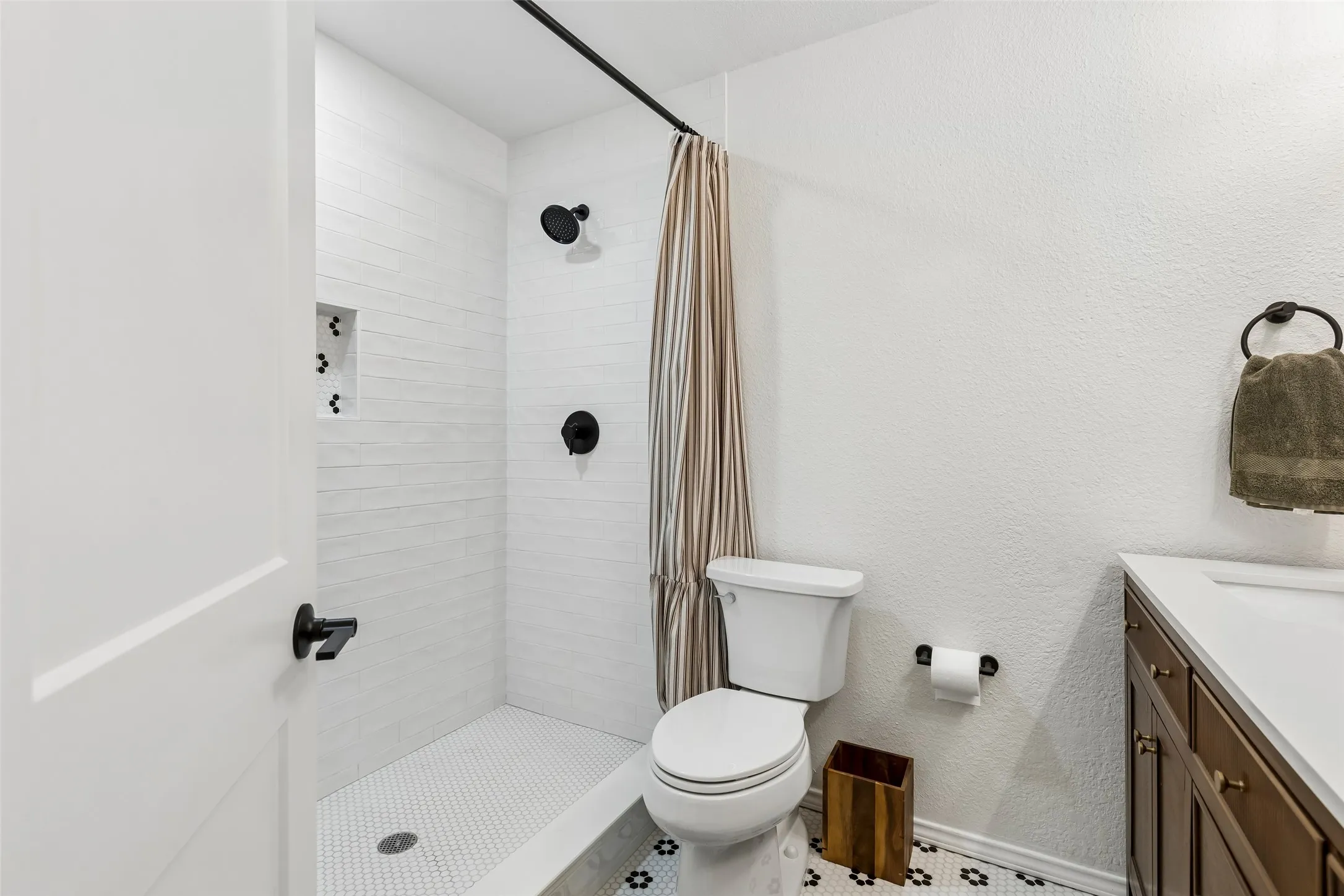 A tiled niche and matte-black fixtures dress up the hall bath's shower without losing everyday function.