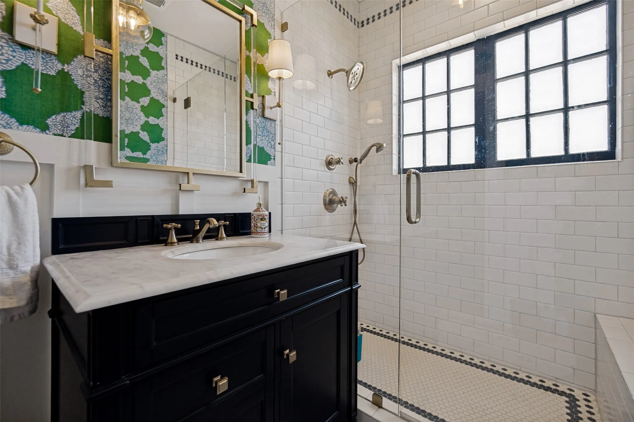 Black vanity with a white countertop and brass hardware