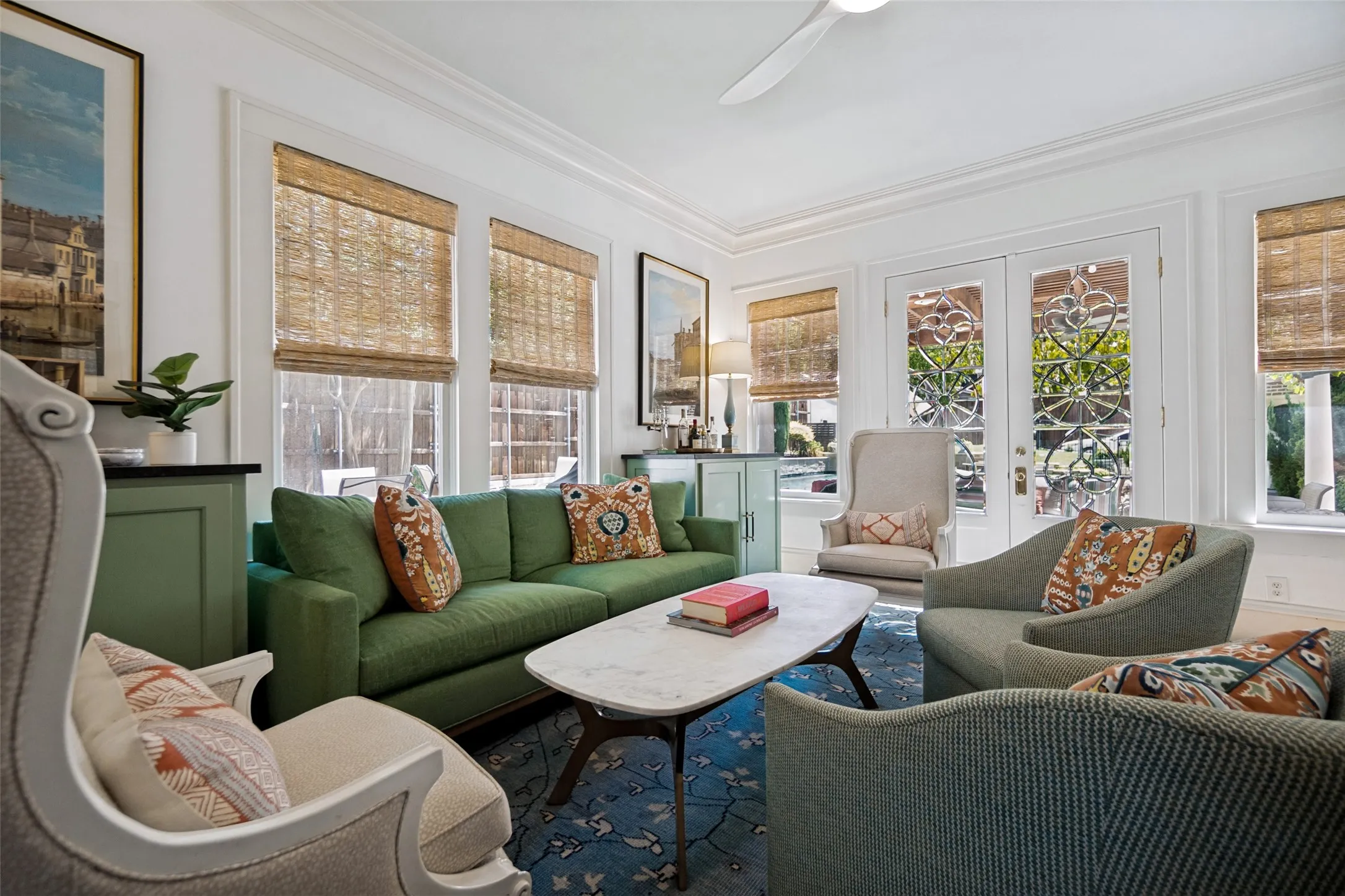 White crown molding, multiple large windows, French doors with decorative glass, recessed lighting, and a ceiling fan