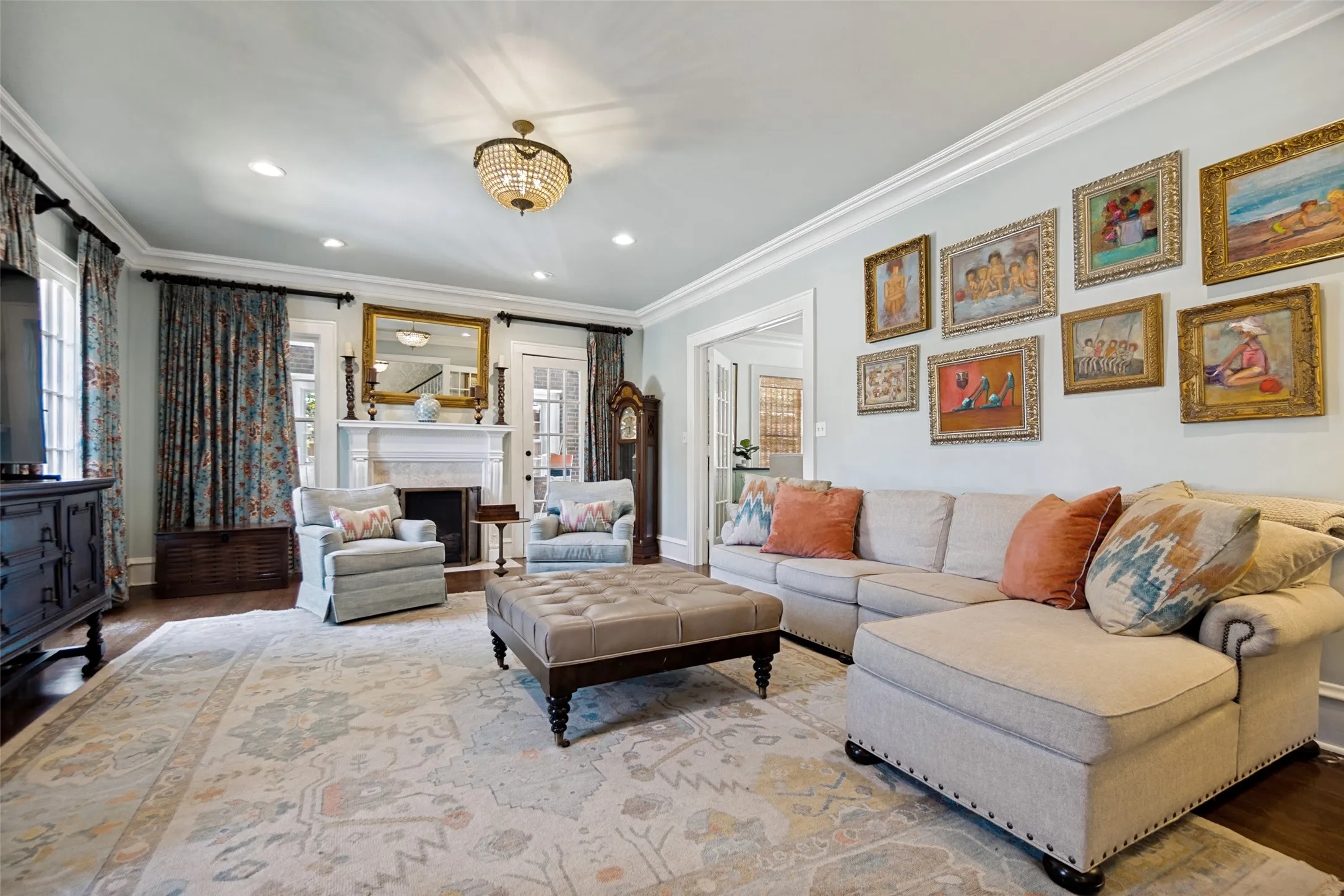 Crown molding details, recessed lighting, and a decorative chandelier illuminate this room