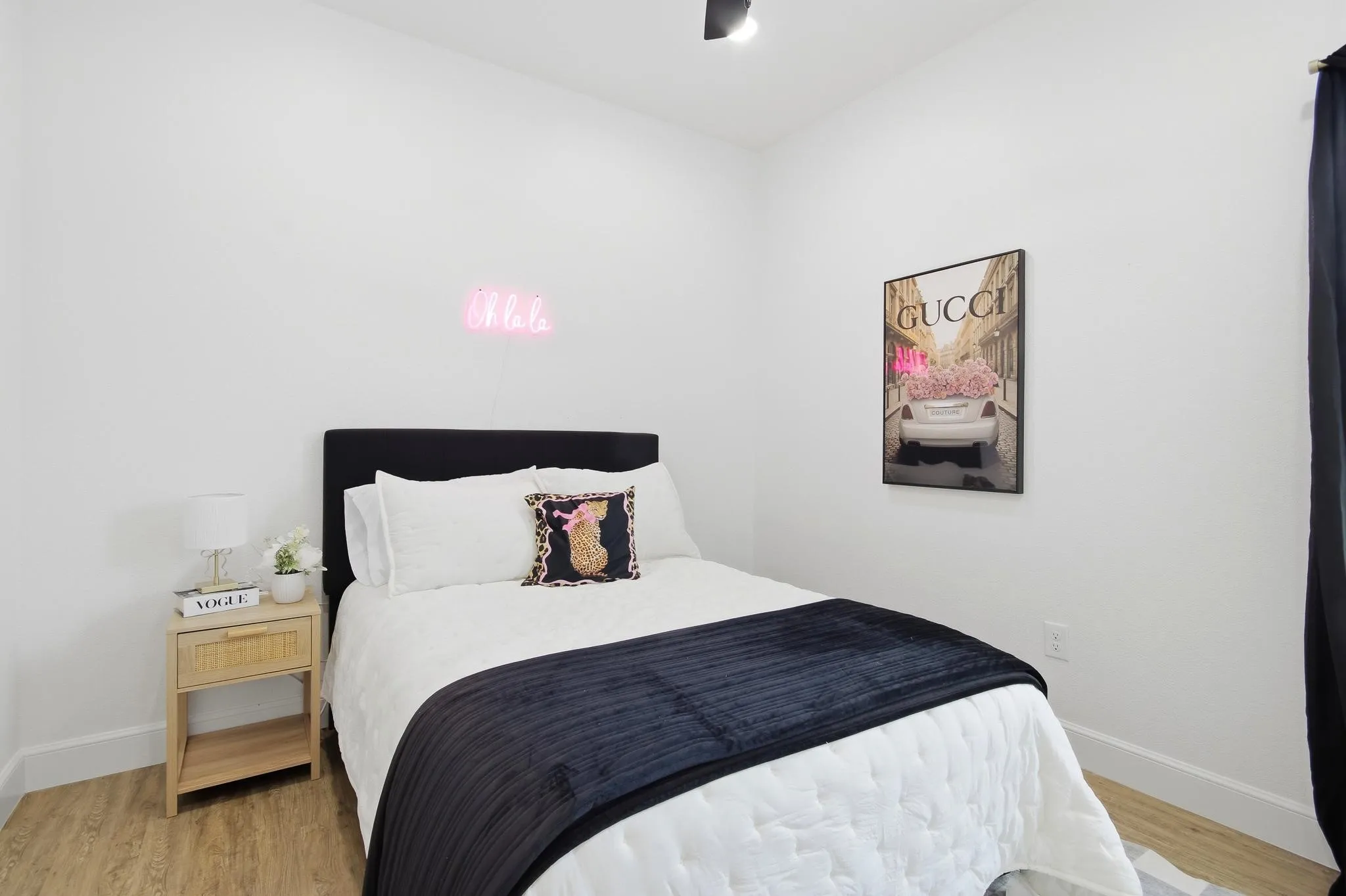 Wood-finish flooring with white wall trim and a black upholstered headboard