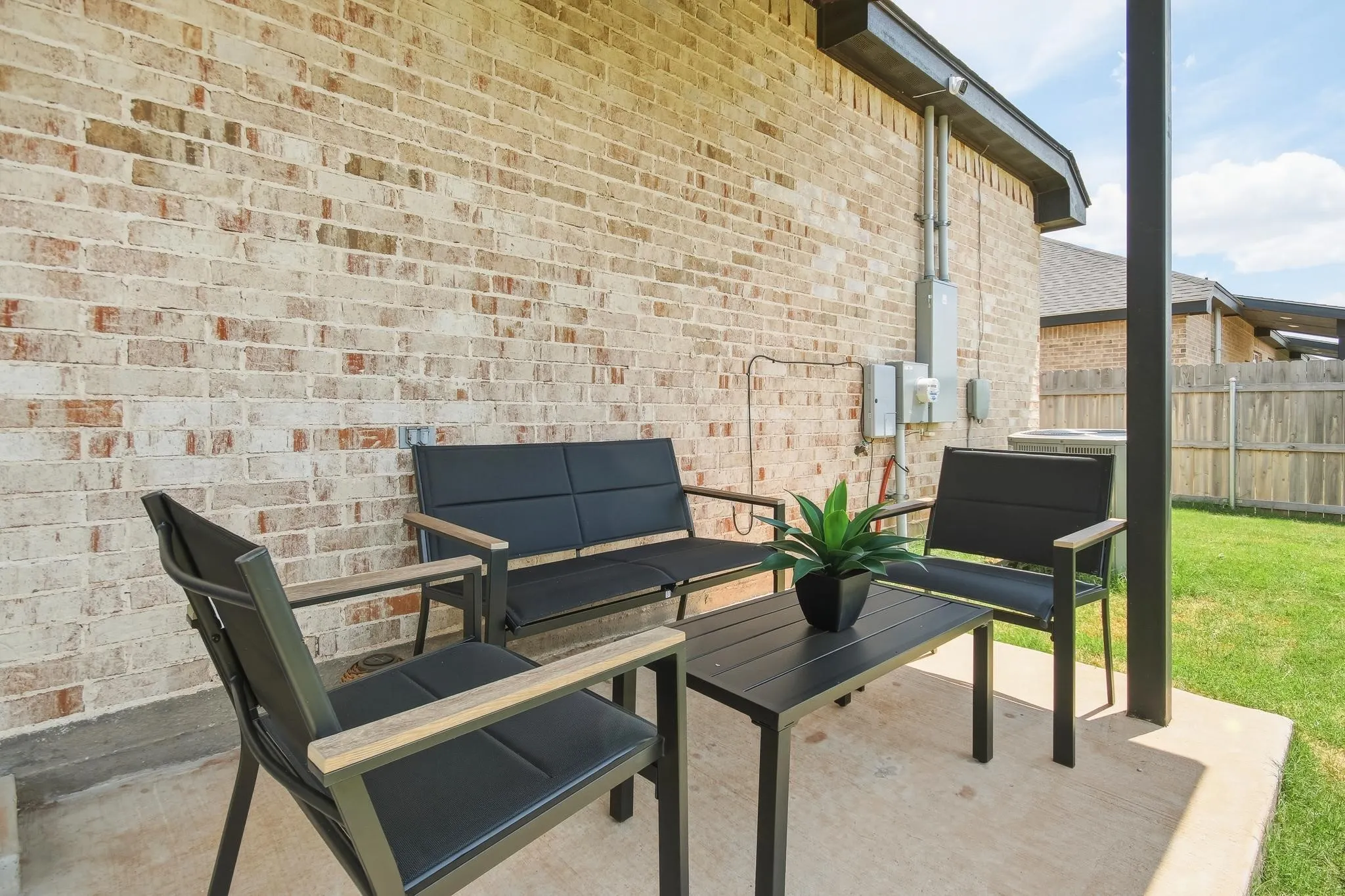 Covered concrete patio with a brick exterior wall