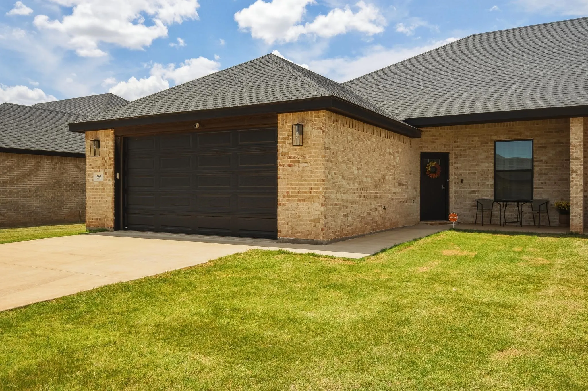 Brick exterior with a dark garage door, concrete driveway, and front entryway
