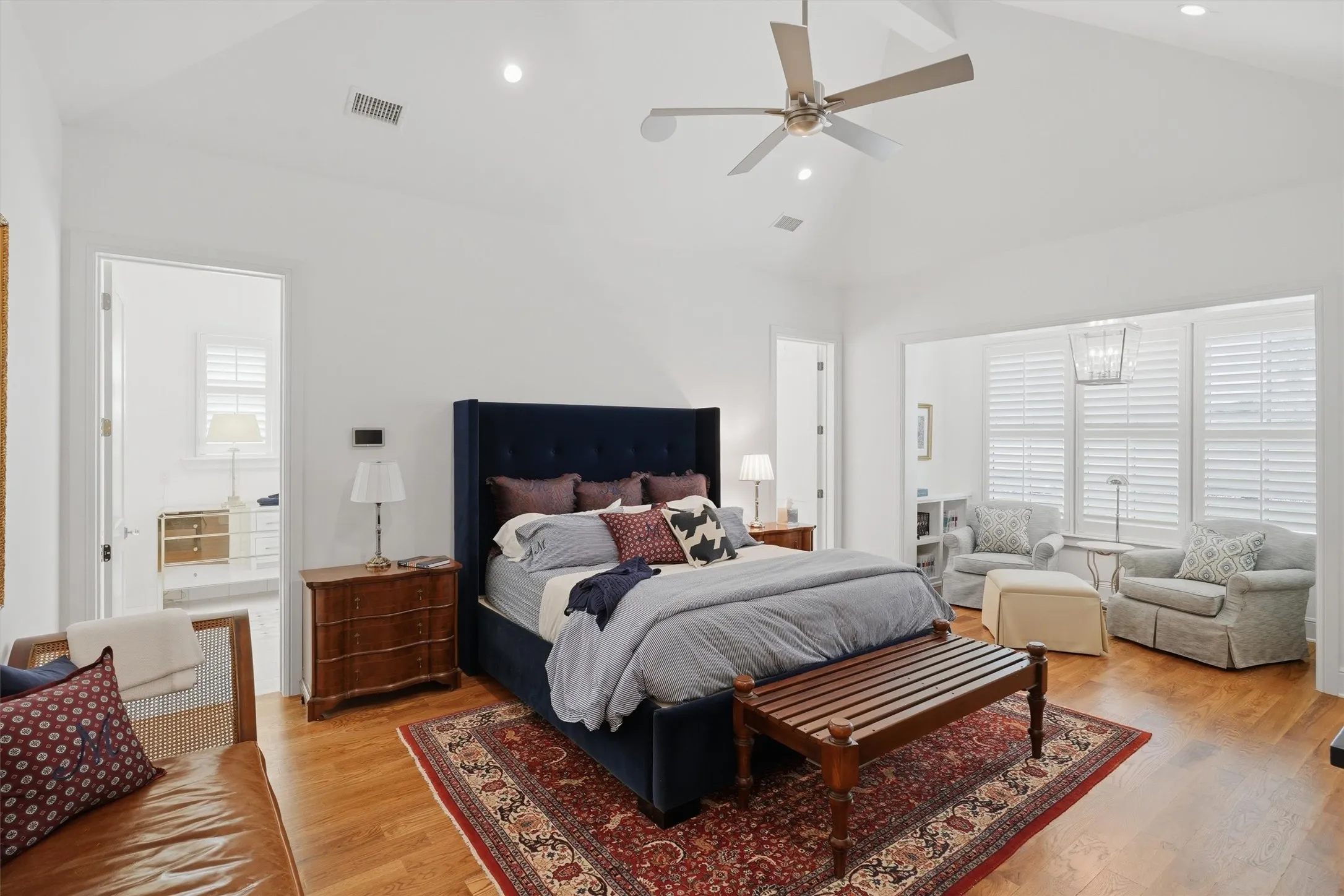 The primary bedroom is filled with natural light. It offers a seating area to relax while enjoying the beautiful finishes of the custom home.