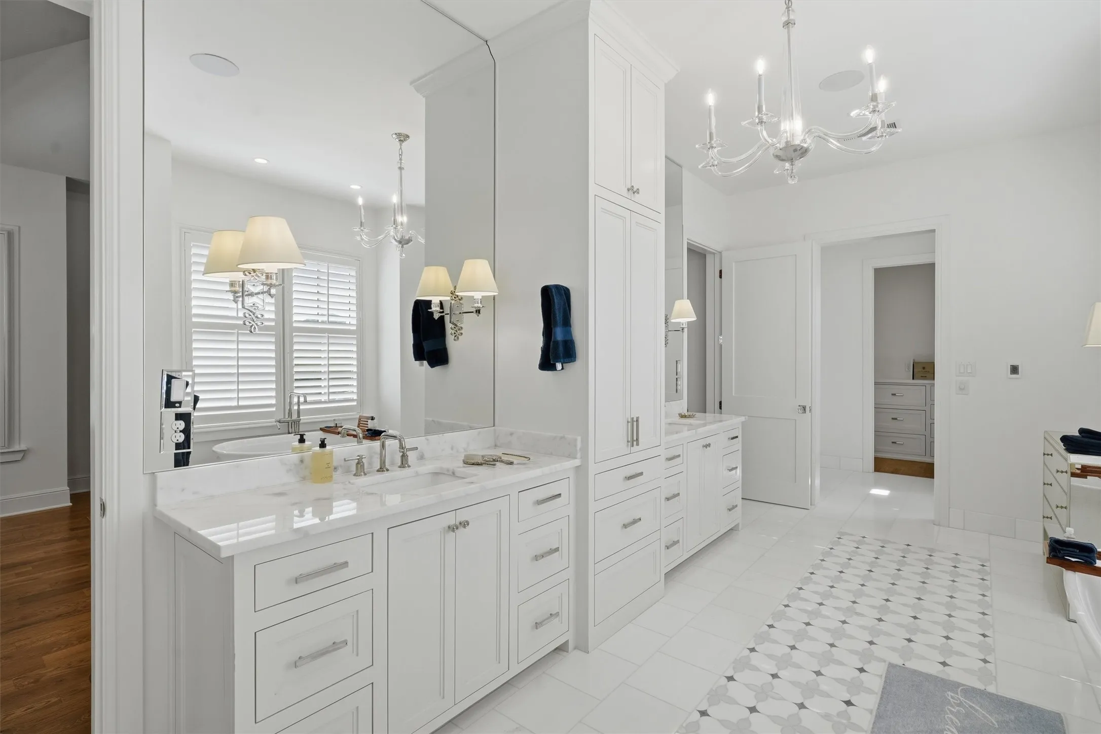 The primary bathroom offers dual vanities, plenty of storage space, and large mirrors that extend to the ceiling. There is ample counter space to get ready while enjoying natural light and heated floors. There is a bathtub and separate walk in shower.