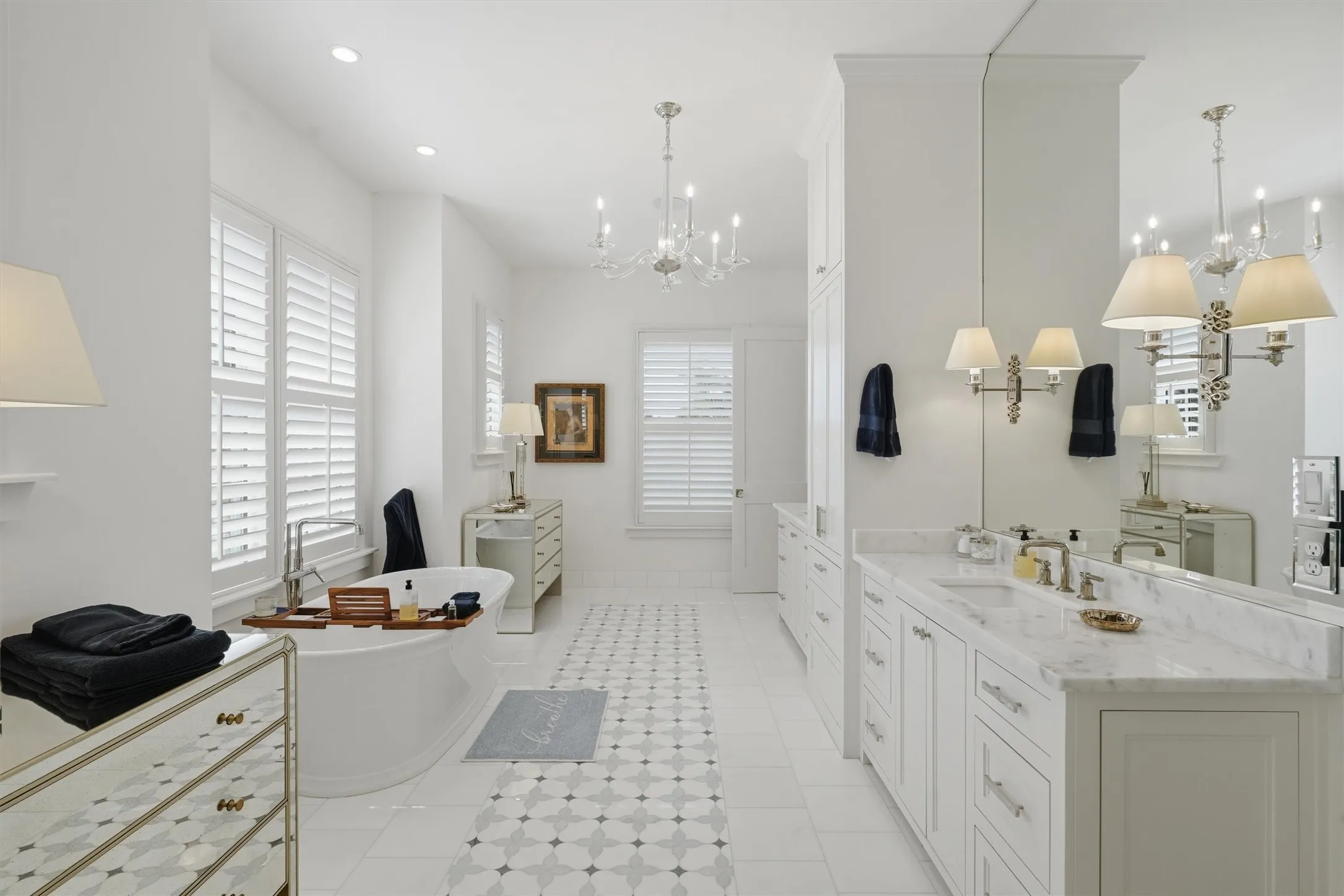 The primary bathroom offers dual vanities, plenty of storage space, and large mirrors that extend to the ceiling. There is ample counter space to get ready while enjoying natural light and heated floors. There is a bathtub and separate walk in shower.
