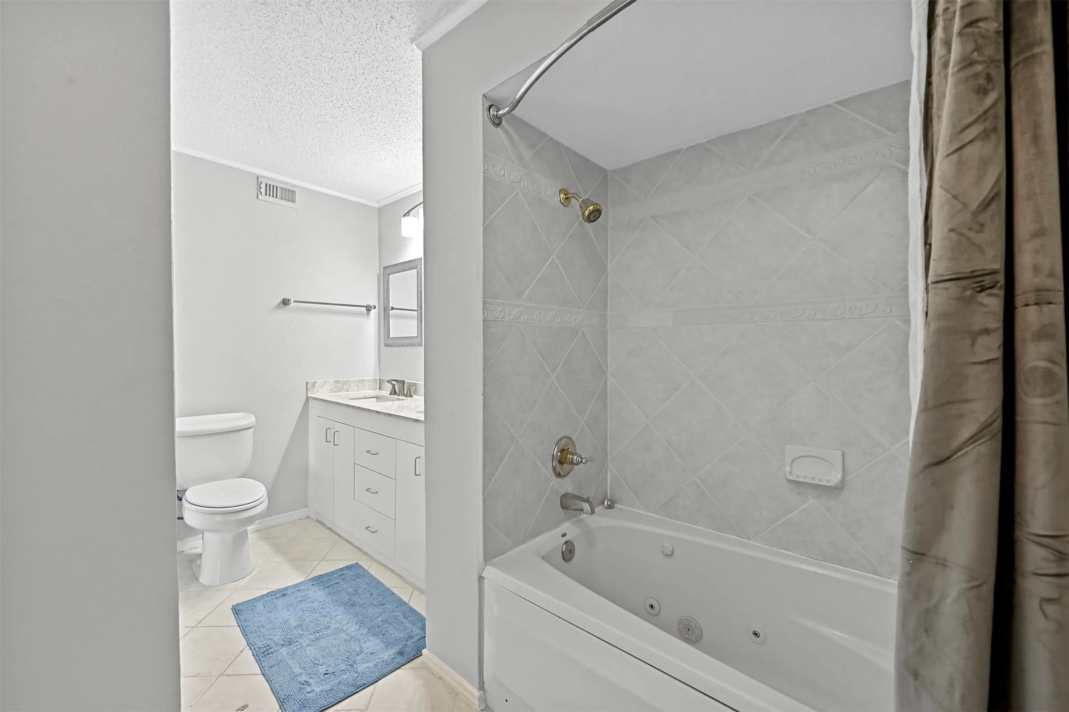 Full bathroom with a textured ceiling, toilet, tile patterned floors, vanity, and ornamental molding