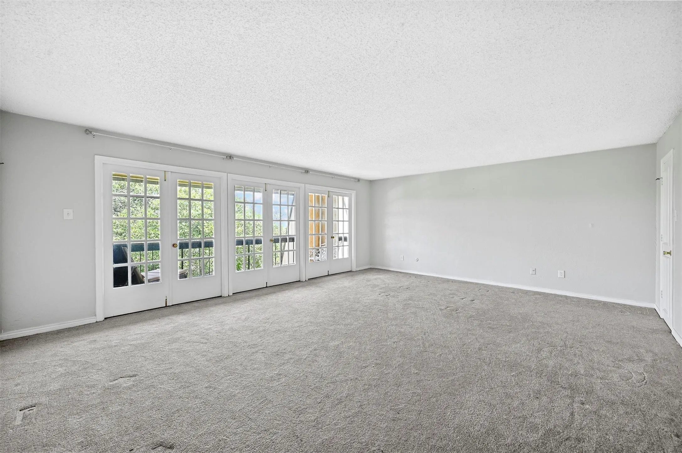Empty room featuring carpet flooring, a textured ceiling, and french doors