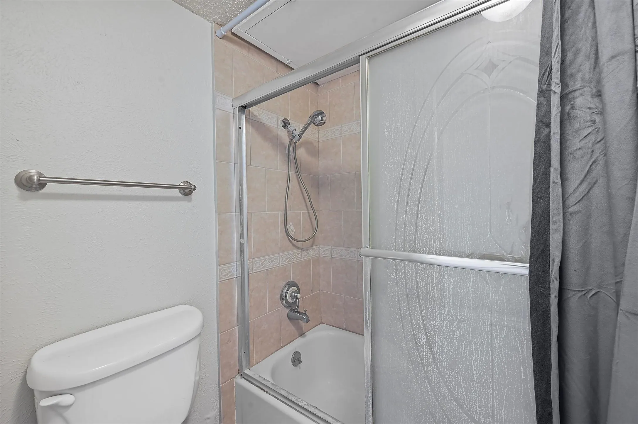 Bathroom with toilet and shower / bath combination with glass door