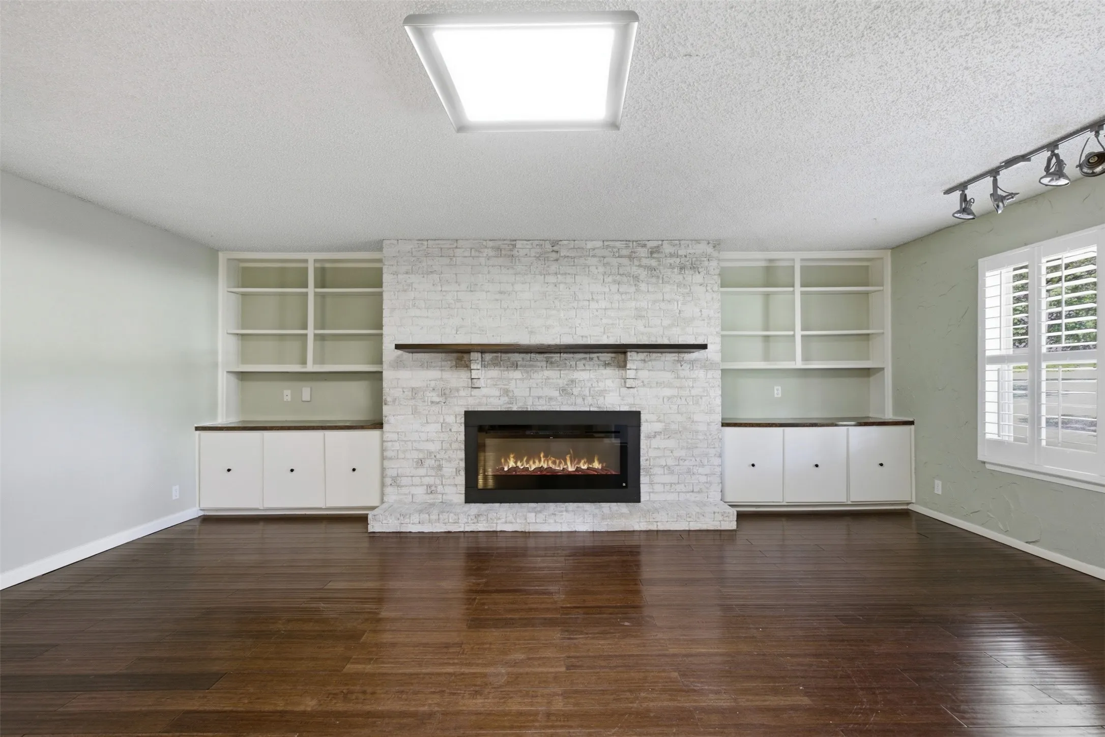 Large living room with electric fireplace and bookcases