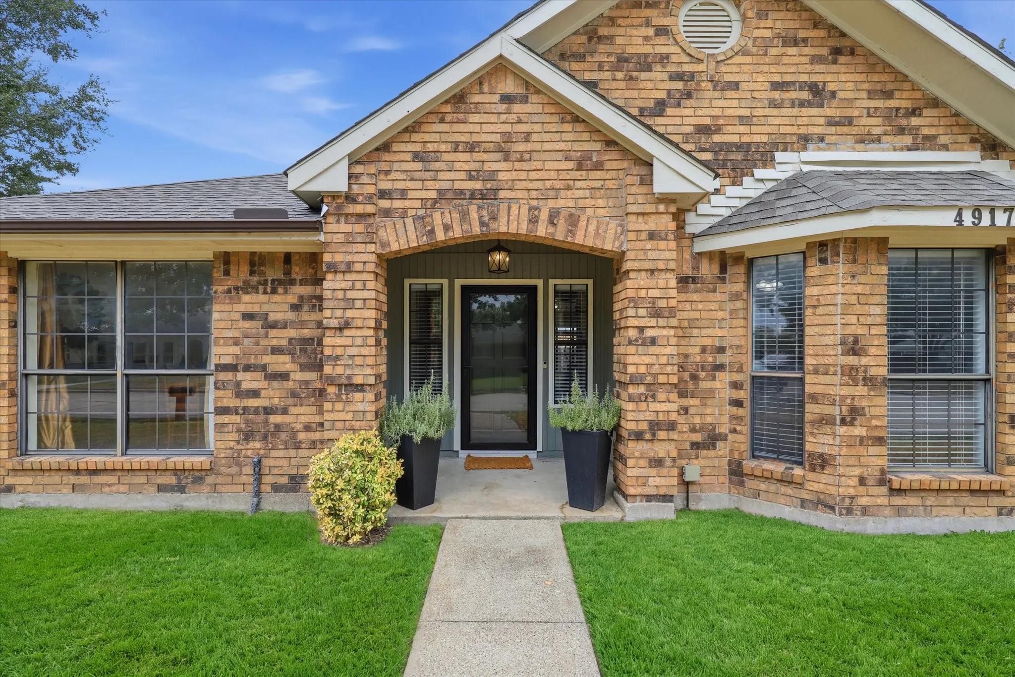 Welcoming covered entry with classic brick detailing and sidelights flanking the front door.