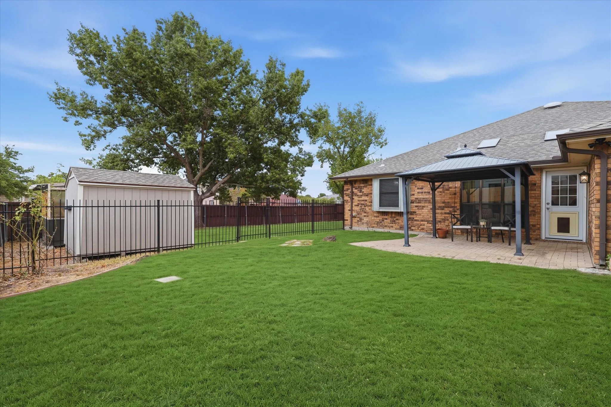 Another view highlights the generous lawn, mature trees, storage shed and additional enclosed outdoor area.