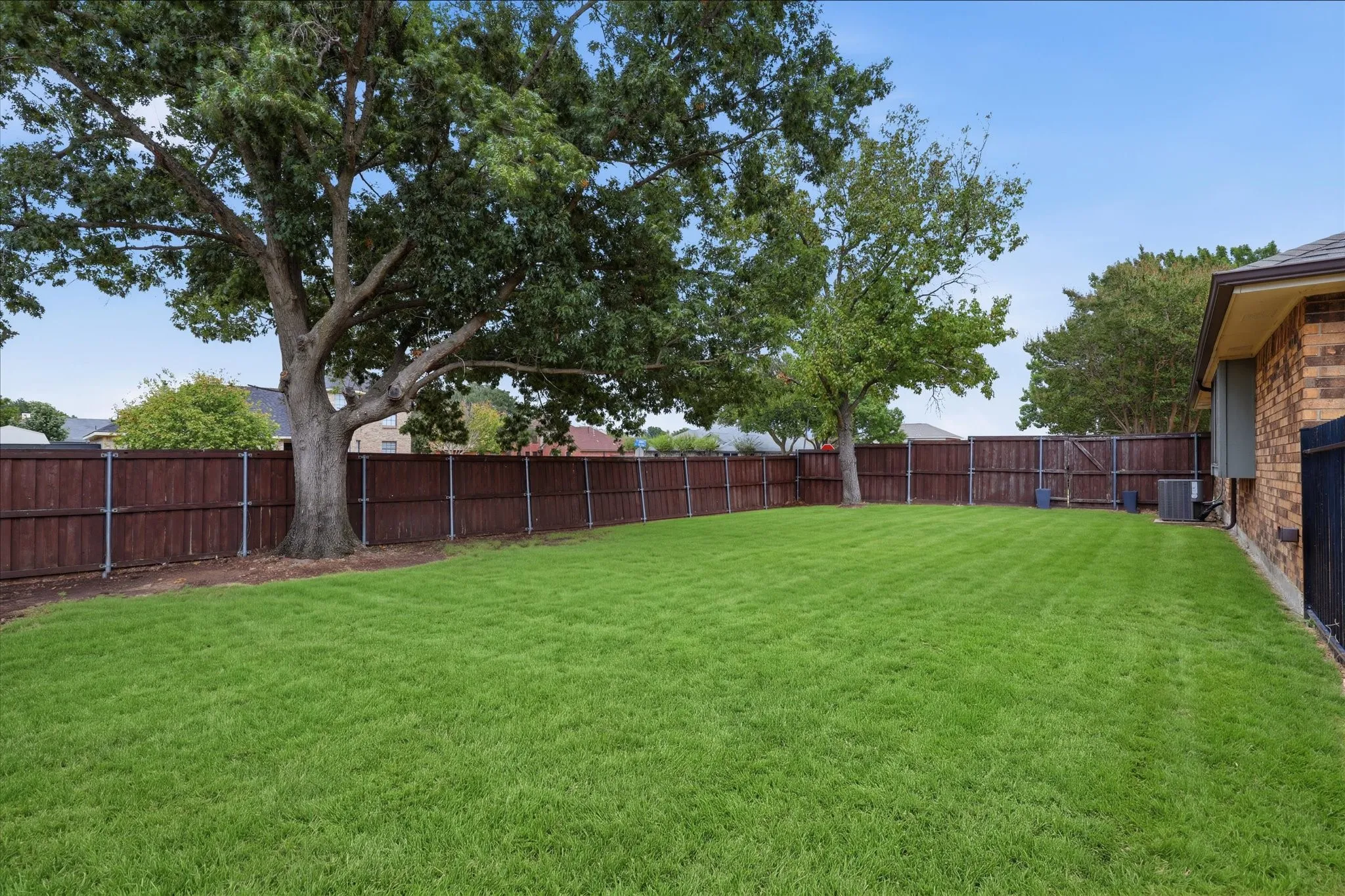 Expansive backyard is framed by mature shade trees with plenty of open lawn for recreation, gardening or future outdoor amenities.