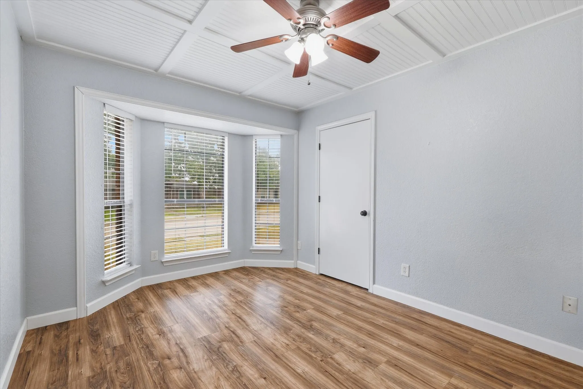 Guest bedroom features laminate wood flooring, a decorative paneled ceiling and a charming bay window—ideal as a bedroom, office or additional living space.