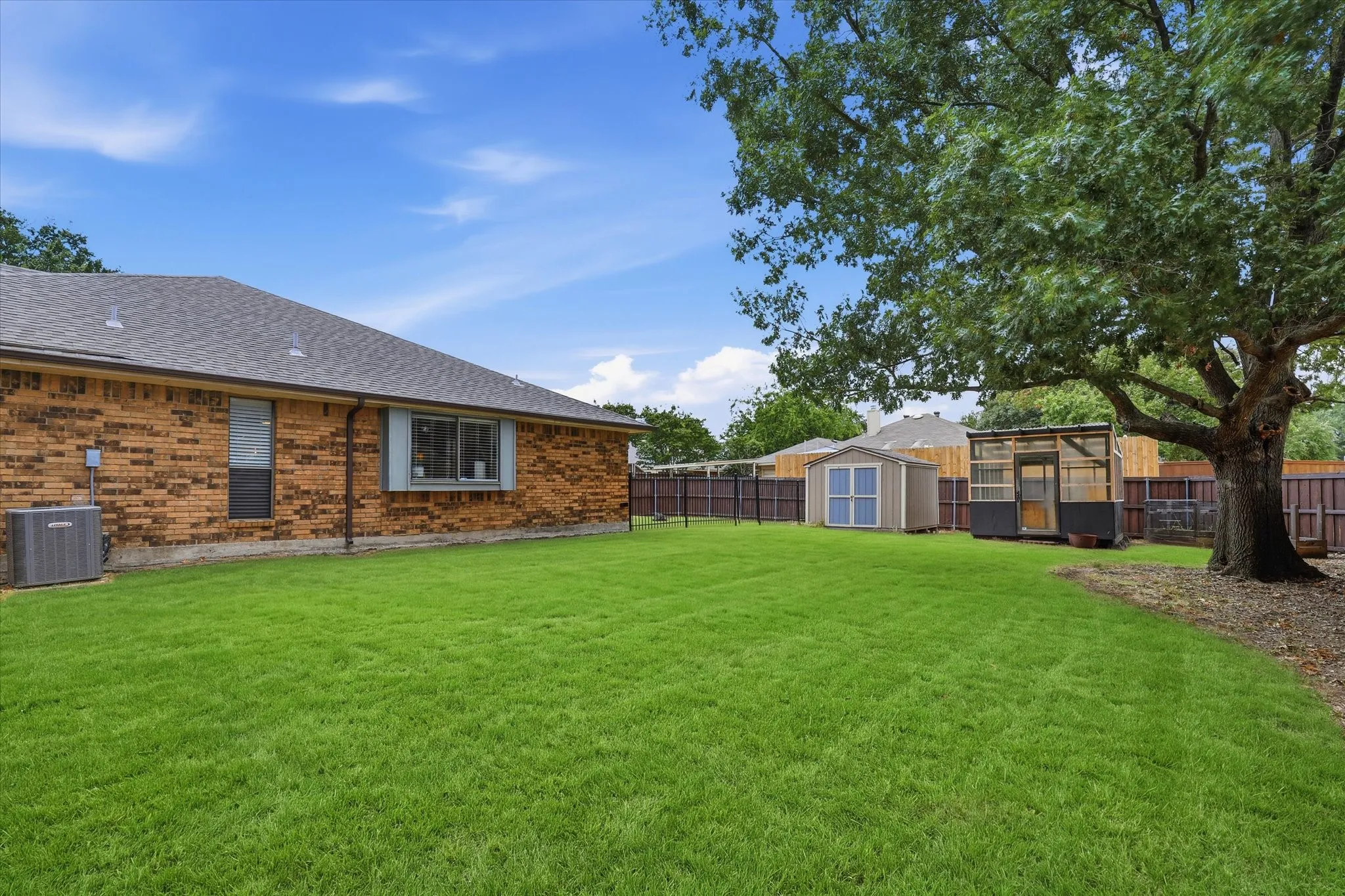 Large corner-lot backyard offers an abundance of usable green space along with a storage shed and greenhouse.
