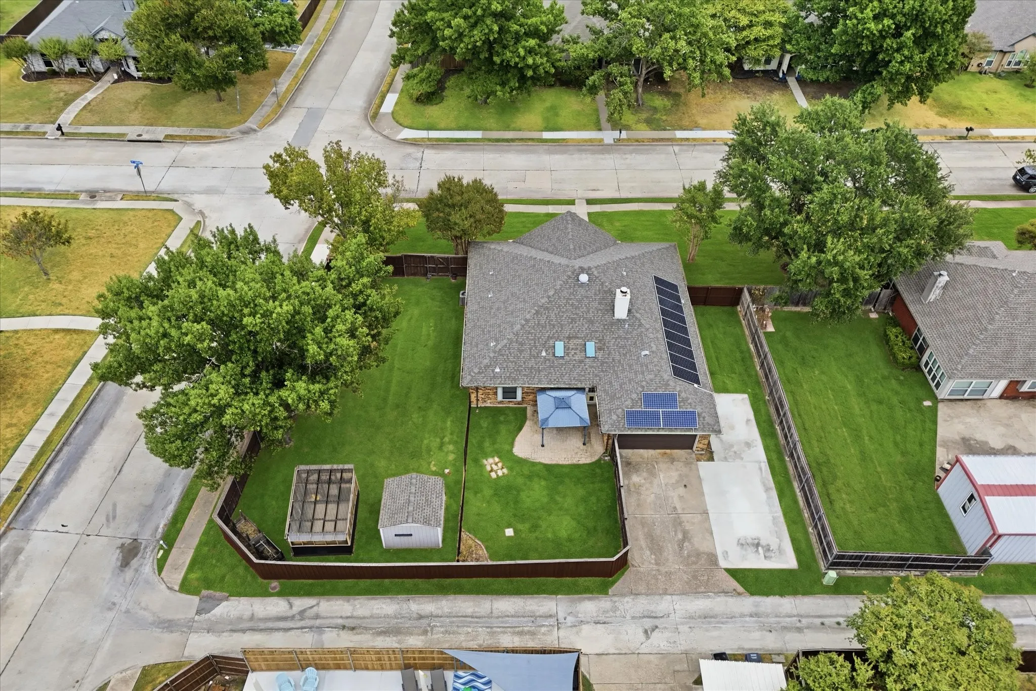 Aerial view showcases the home's single-story design, expansive corner lot, and mature trees.