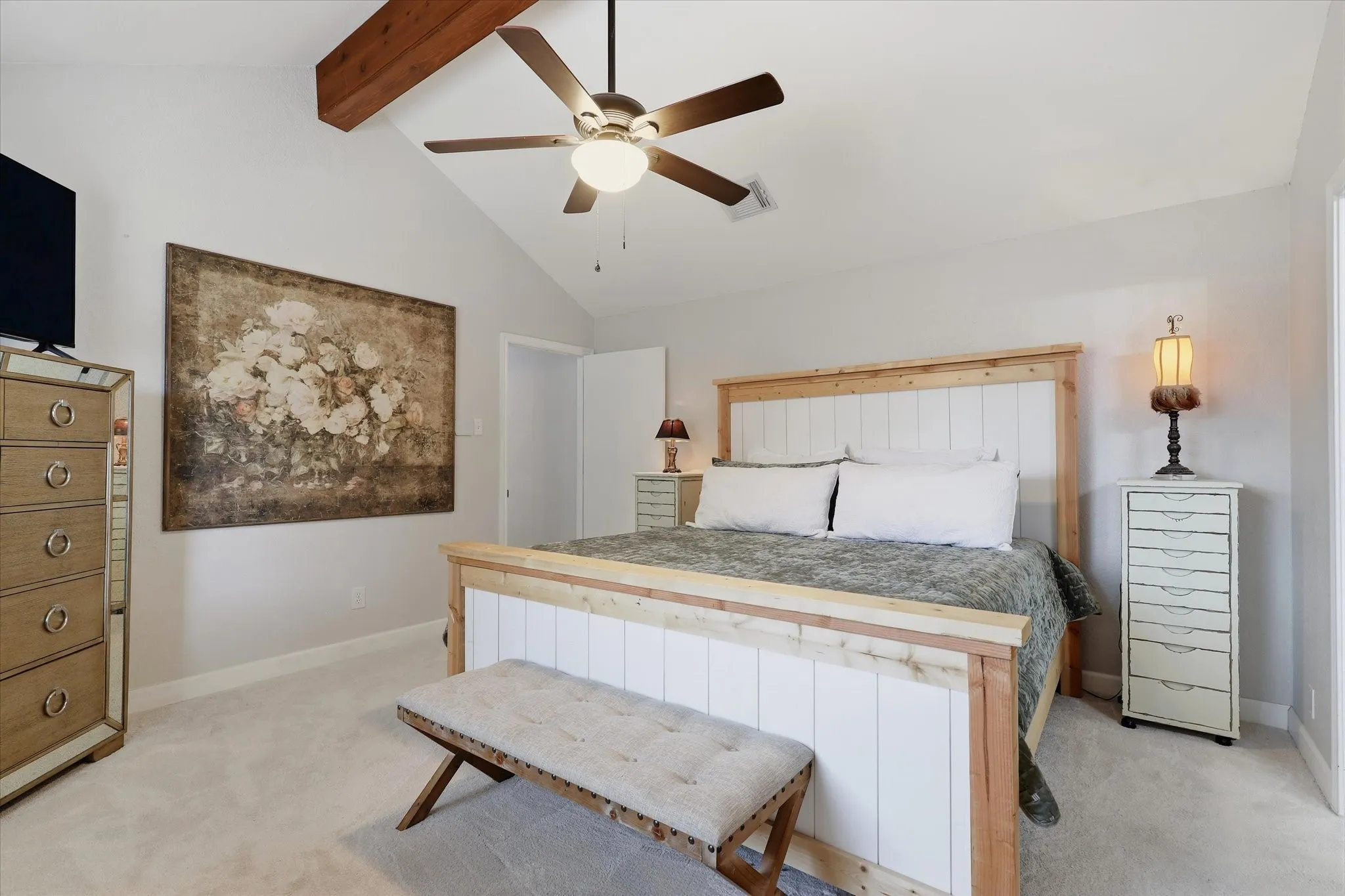 Vaulted ceilings and an exposed wood beam add architectural character to the spacious primary retreat.