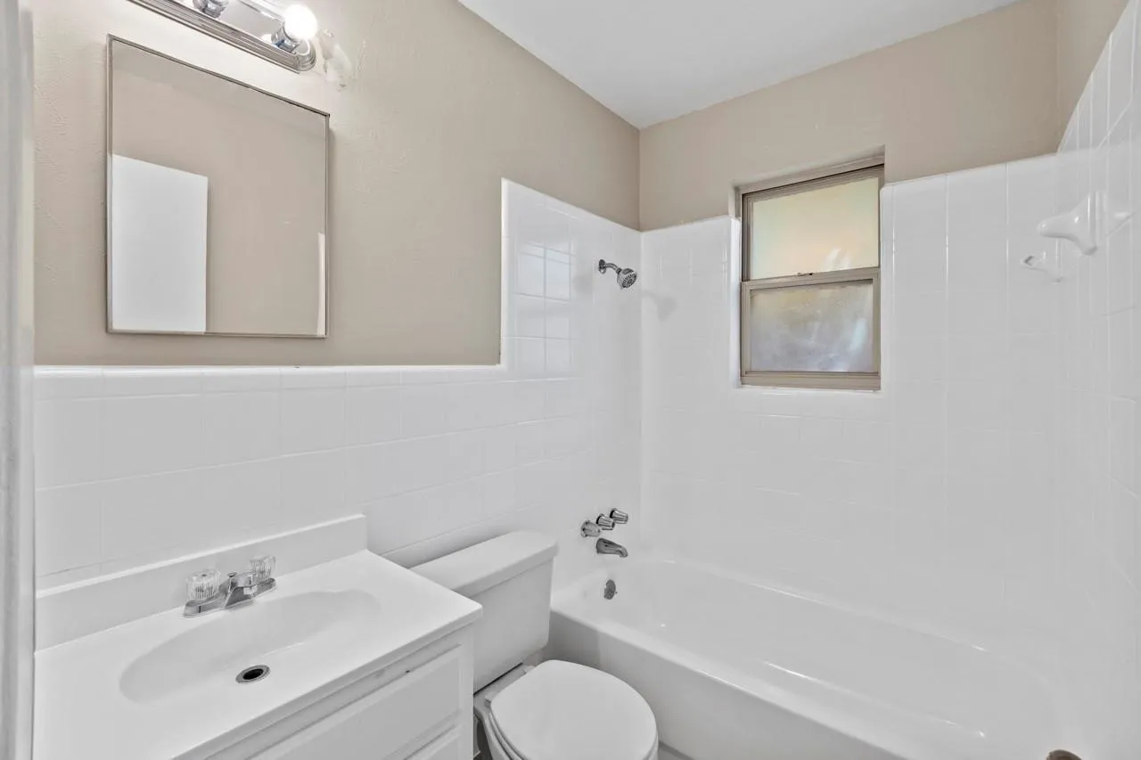 White tile surround bathtub with integrated showerhead and faucet