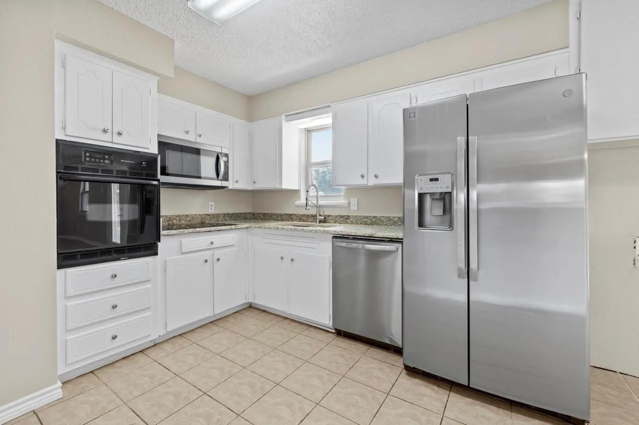 White cabinetry, stainless steel appliances, built-in double oven, built-in microwave, and tile flooring
