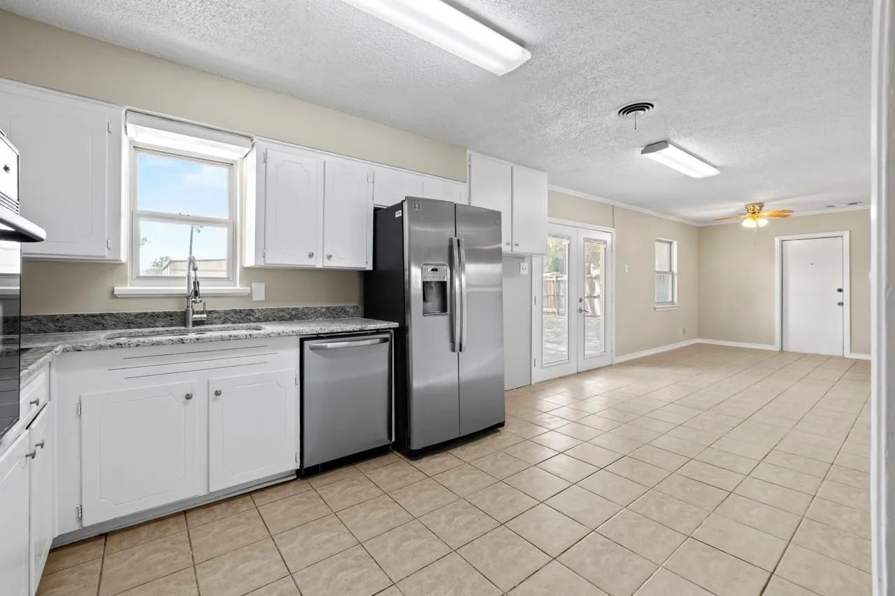 Kitchen featuring white cabinetry, stainless steel appliances, and light-toned tile flooring