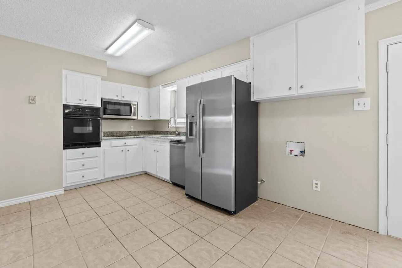 Kitchen featuring white cabinetry, built-in oven, built-in microwave, stainless steel refrigerator, and tile flooring