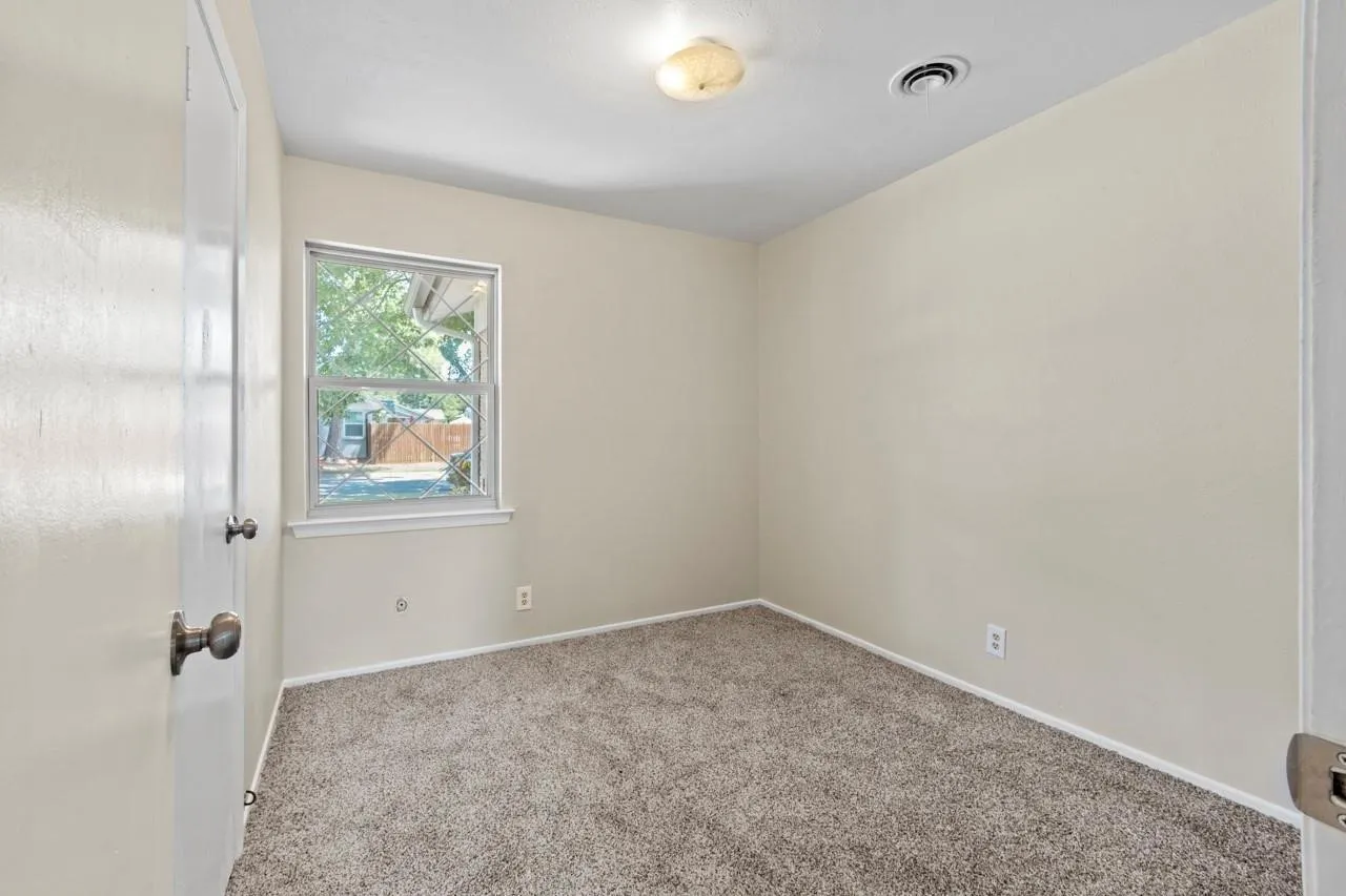 Wall-to-wall carpeting with light-toned walls and a single window
