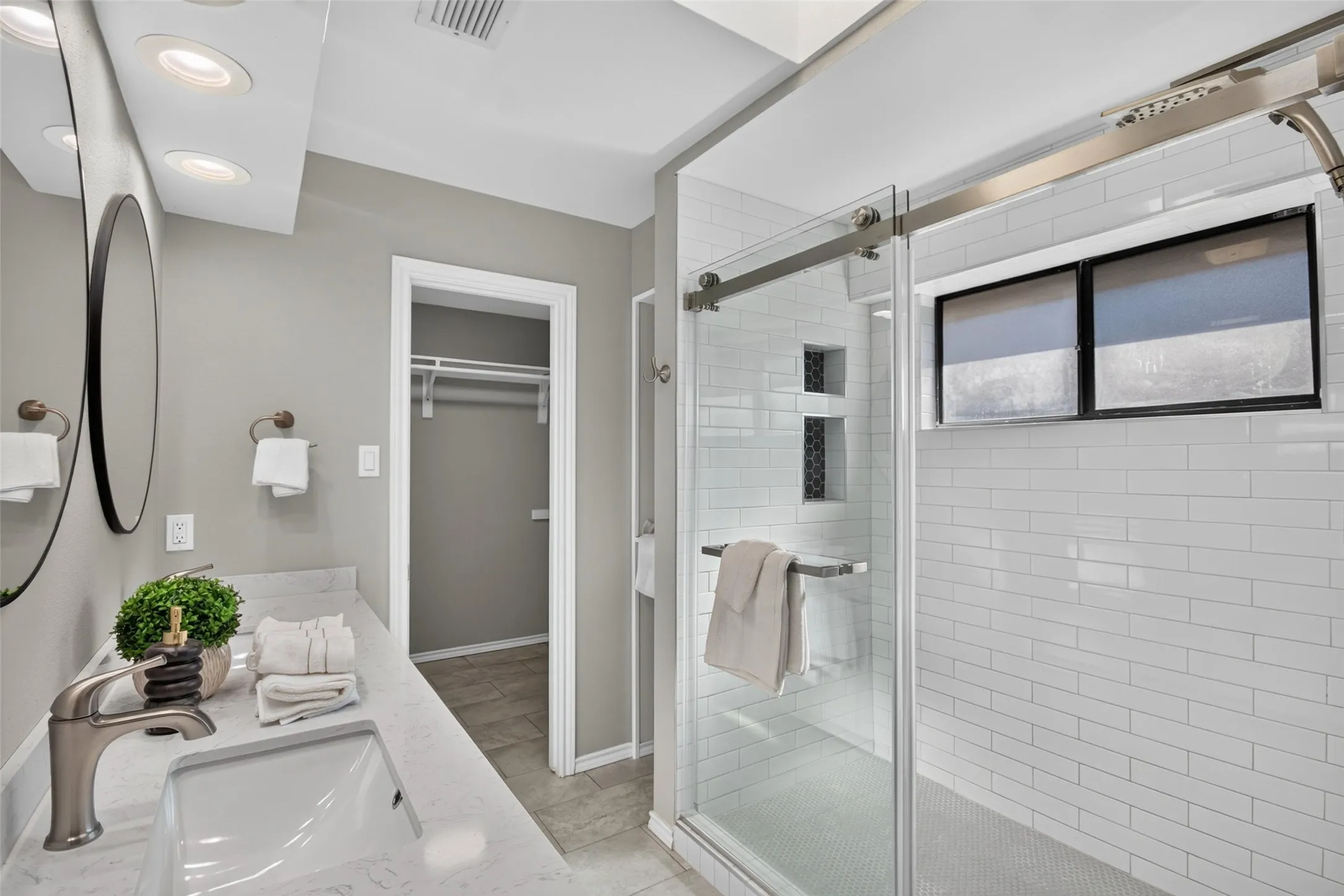 Bathroom featuring a vanity with an undermount sink and a polished chrome faucet, dual circular mirrors, and recessed lighting