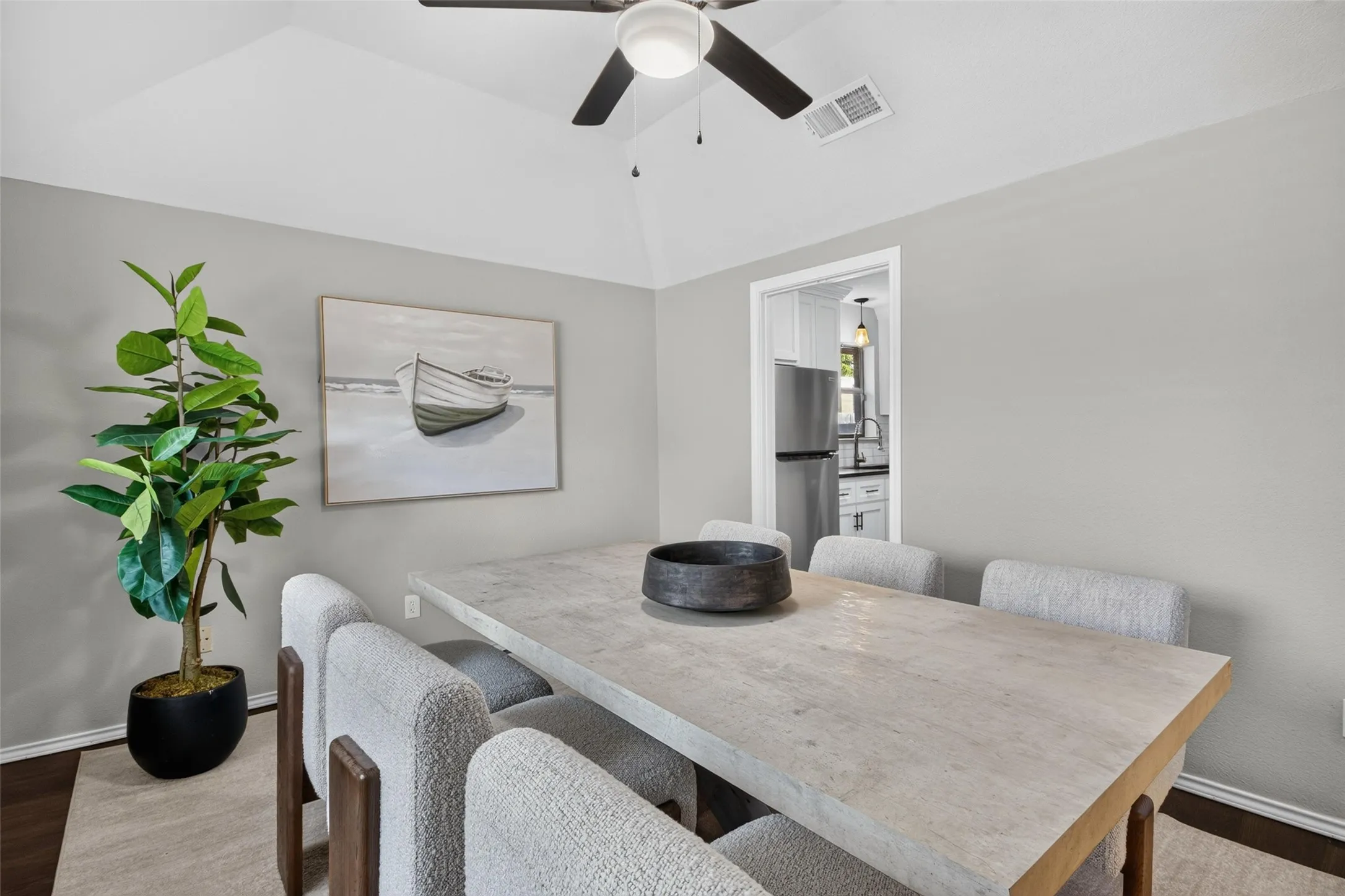 Vaulted ceiling with a ceiling fan, recessed doorway, and wood-finish flooring