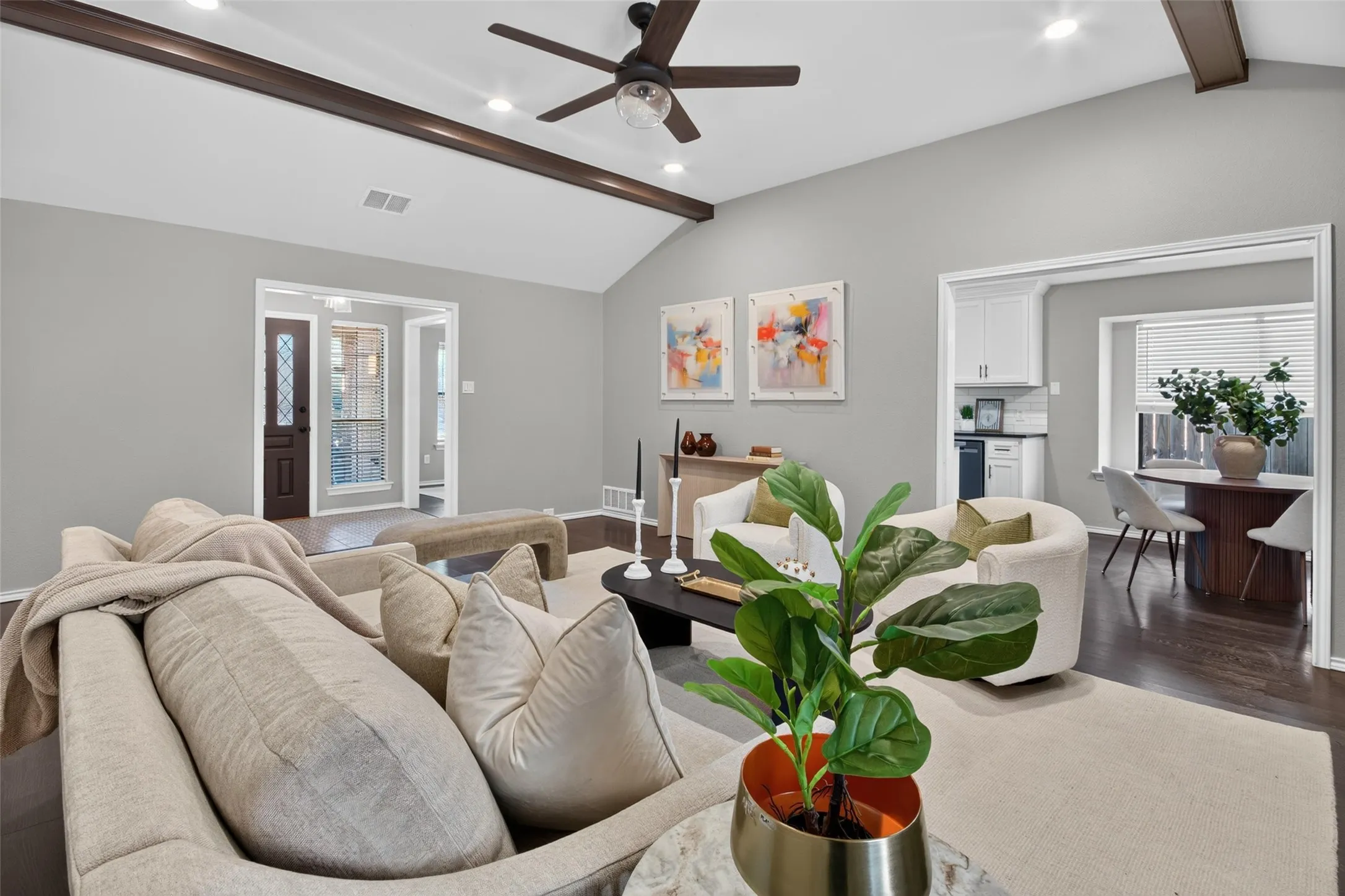 Vaulted ceiling with exposed beams, recessed lighting, wood-finish flooring, and a decorative front entry door with leaded glass