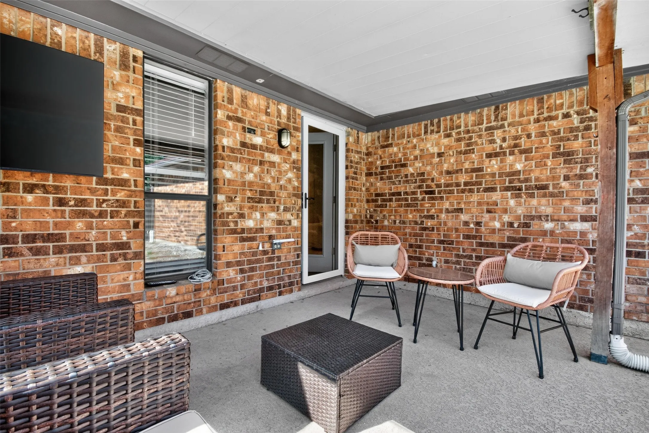 Covered patio featuring brick exterior walls and a concrete surface