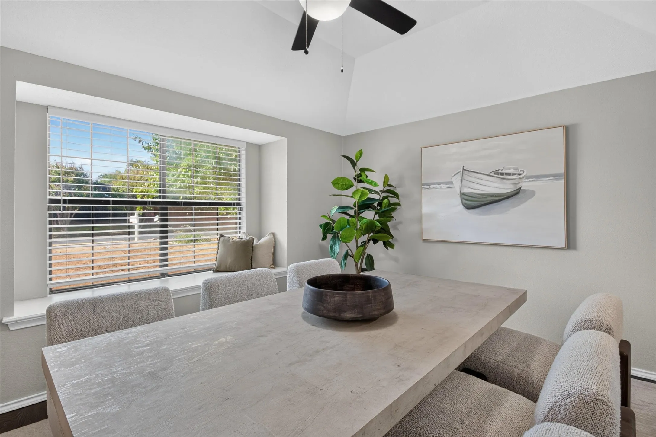 Vaulted ceiling, ceiling fan, expansive bay window, window seat, and neutral wall finishes