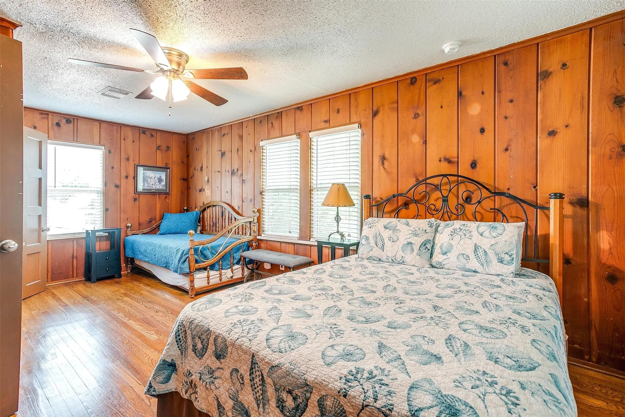 Wood-paneled walls and wood-finish flooring with a ceiling fan and multiple windows