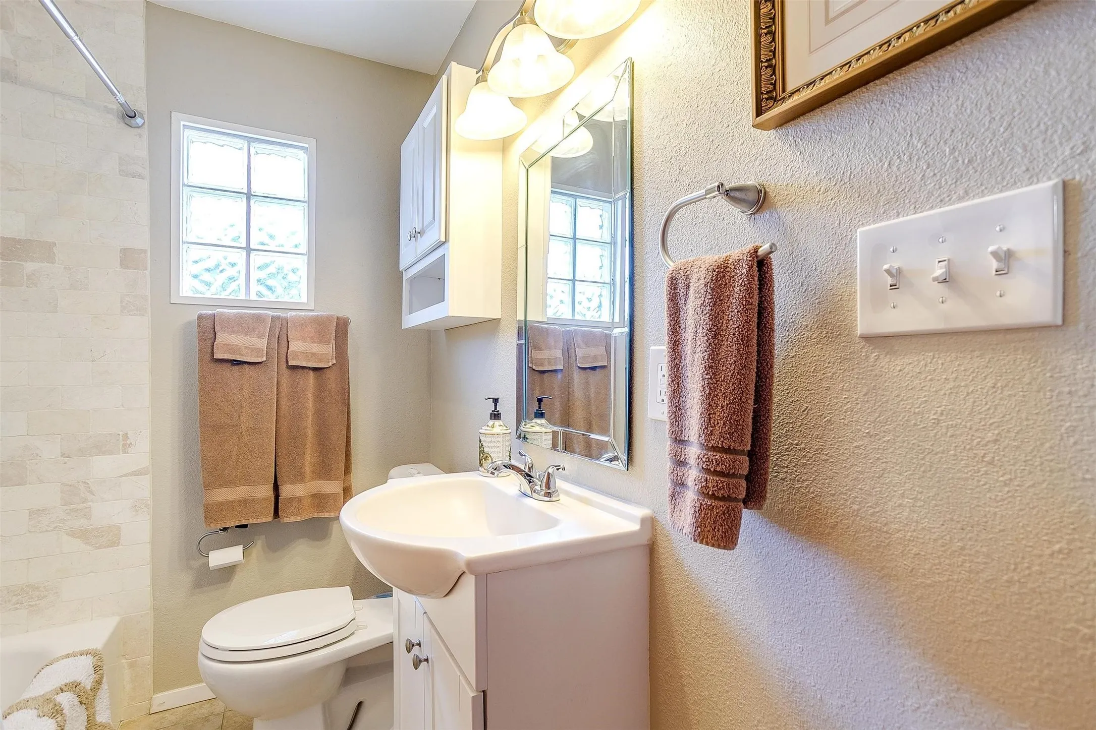 White vanity with a ceramic basin, chrome faucet, and mirrored medicine cabinet