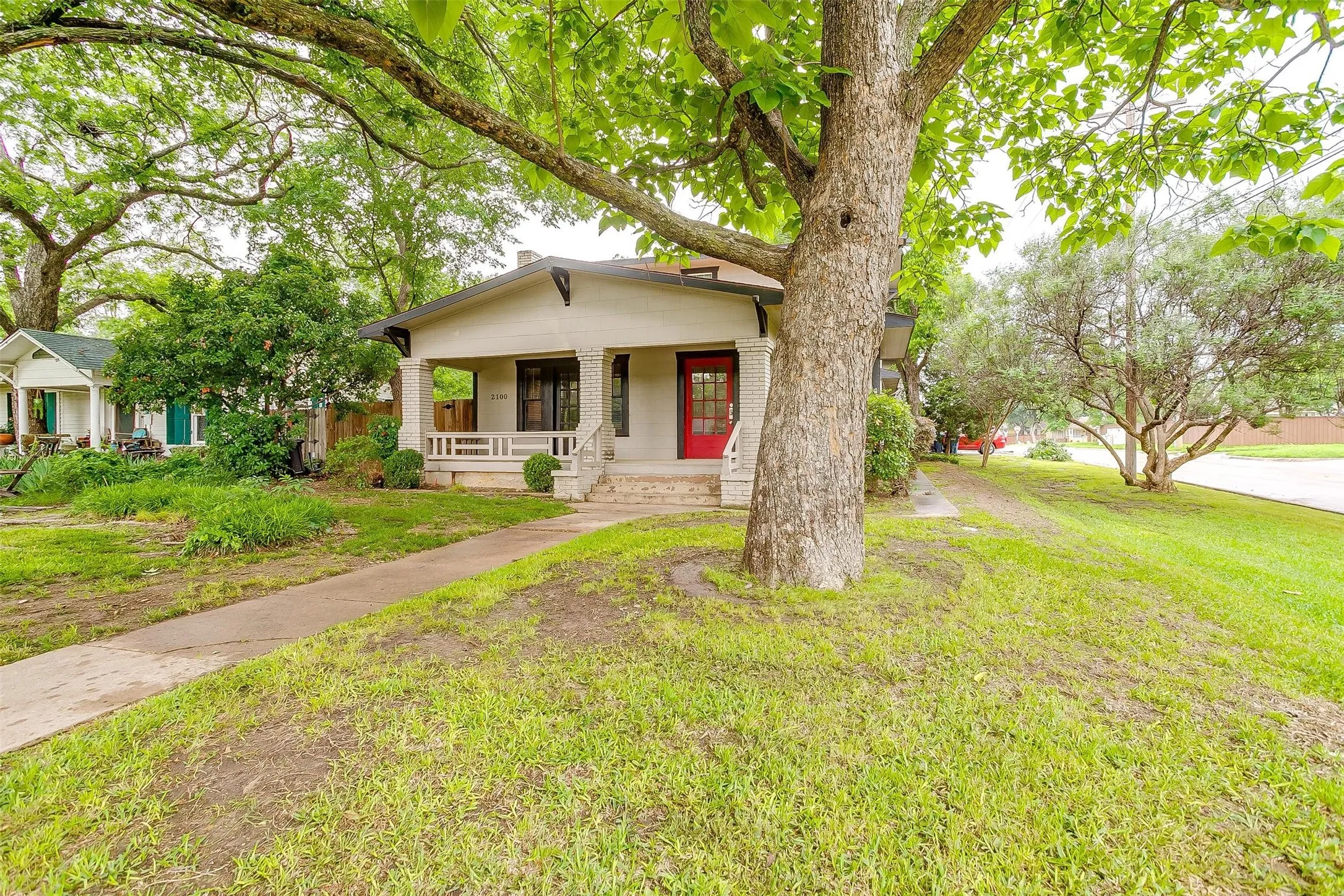 Stucco exterior with a covered front porch, stone porch columns, and a red front door
