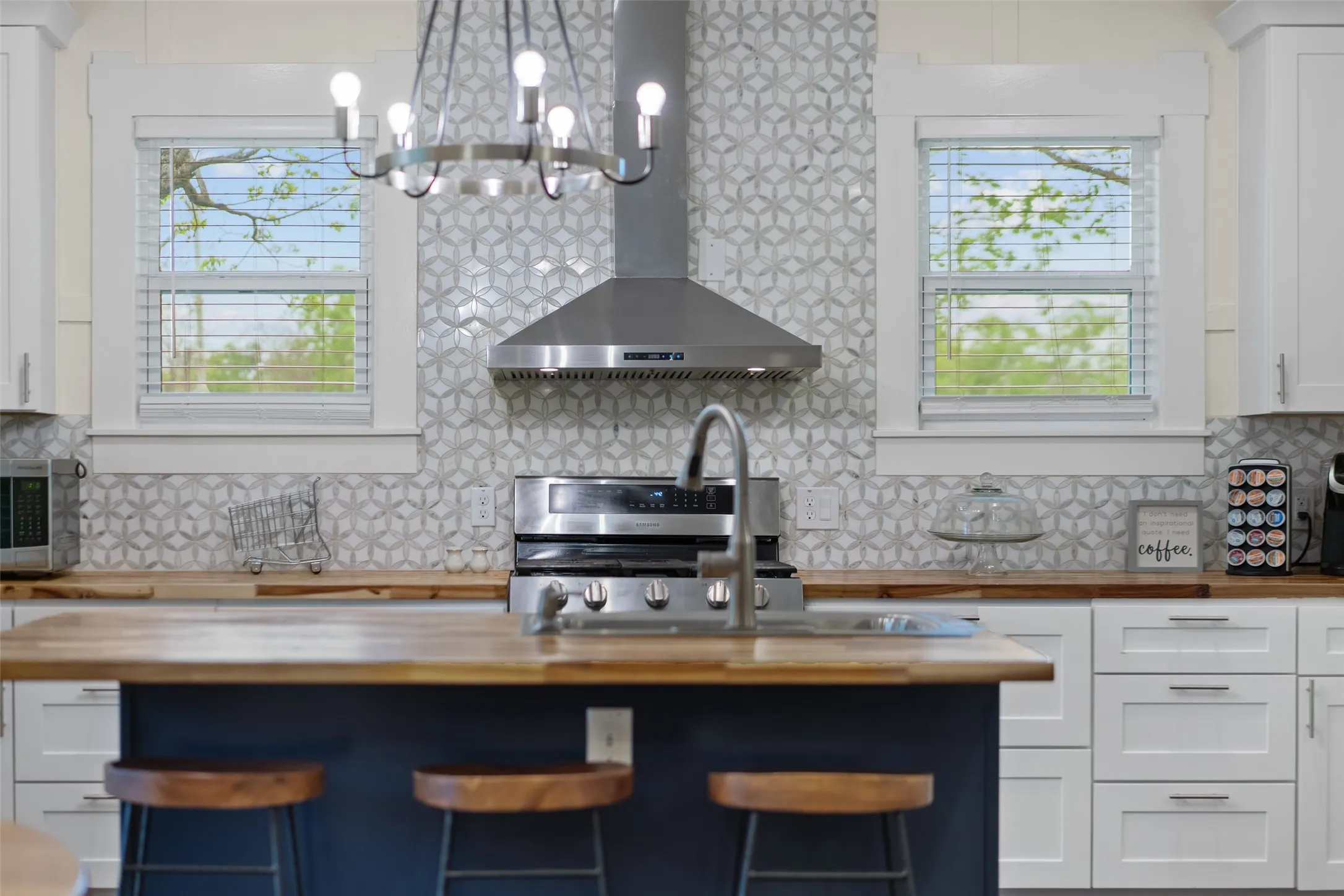 Beautiful kitchen with gas range, custom hood, & white cabinetry.
