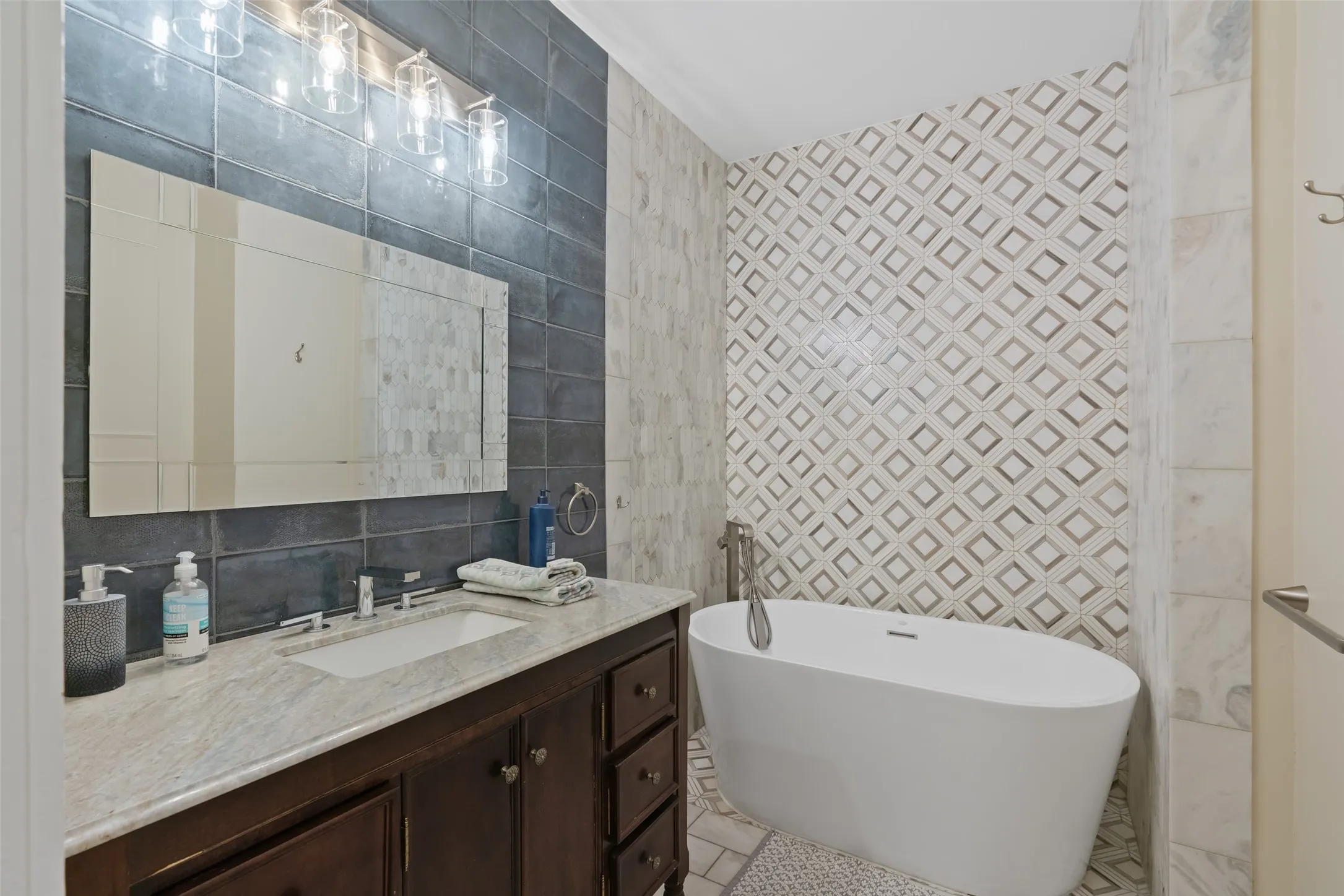 Freestanding soaking tub, marble-top vanity, & beautiful tilework.