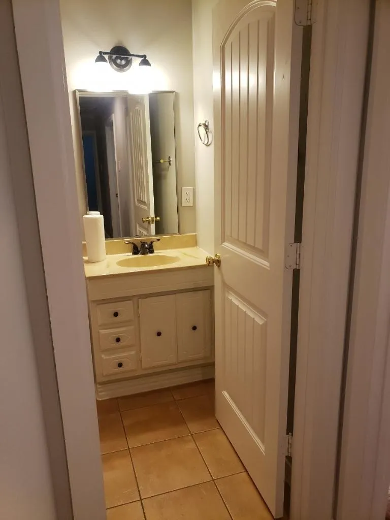 Vanity with a single basin, wall-mounted light fixture, and tile flooring